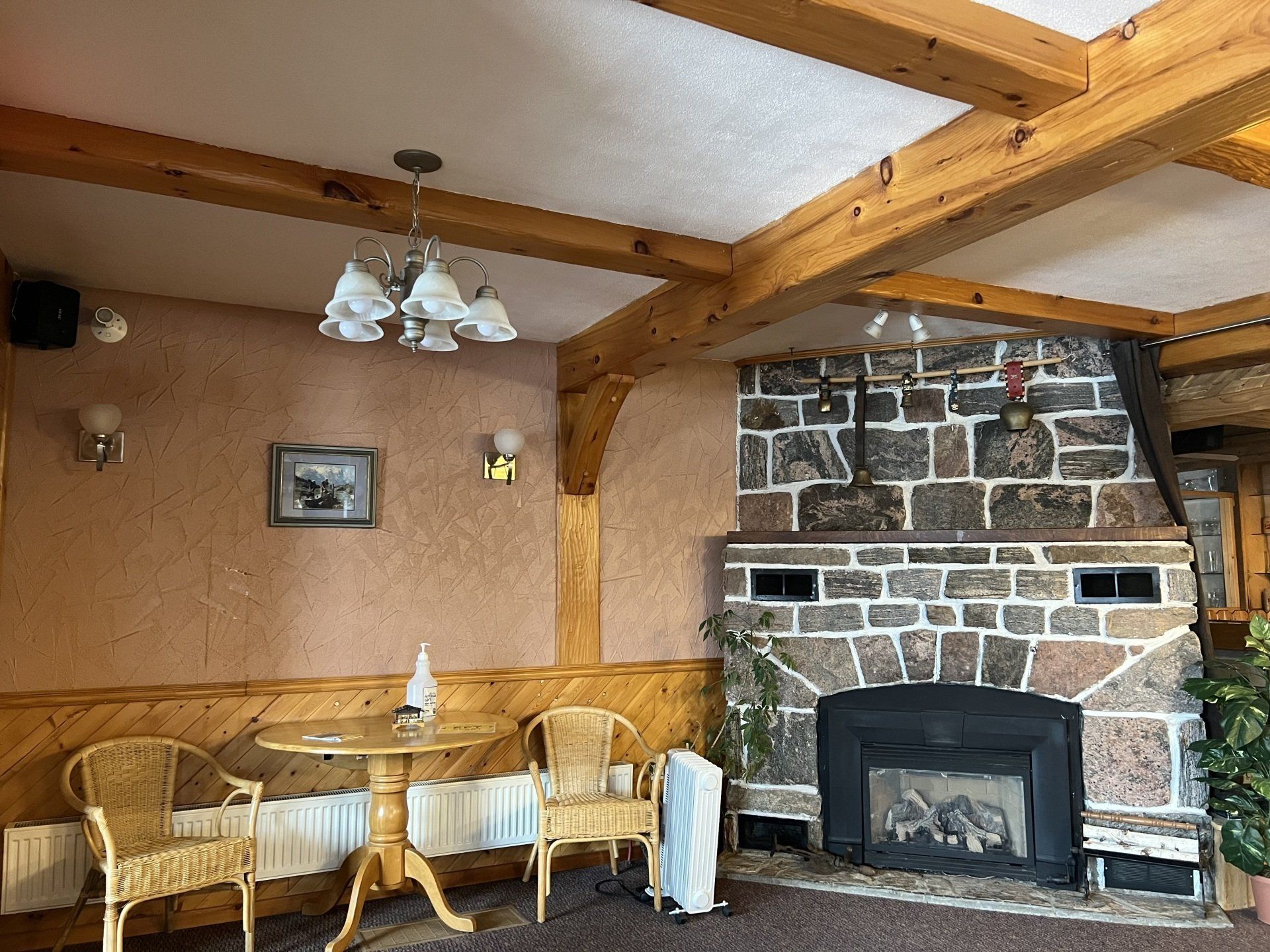 Cozy rustic living room with a stone fireplace, wood beams, wicker chairs, and warm tan walls