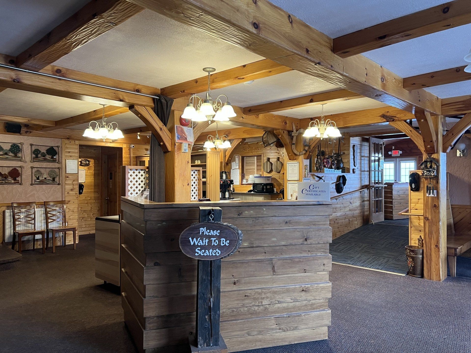 Rustic lodge lobby with wooden beams, stone counter, and warm hanging lights