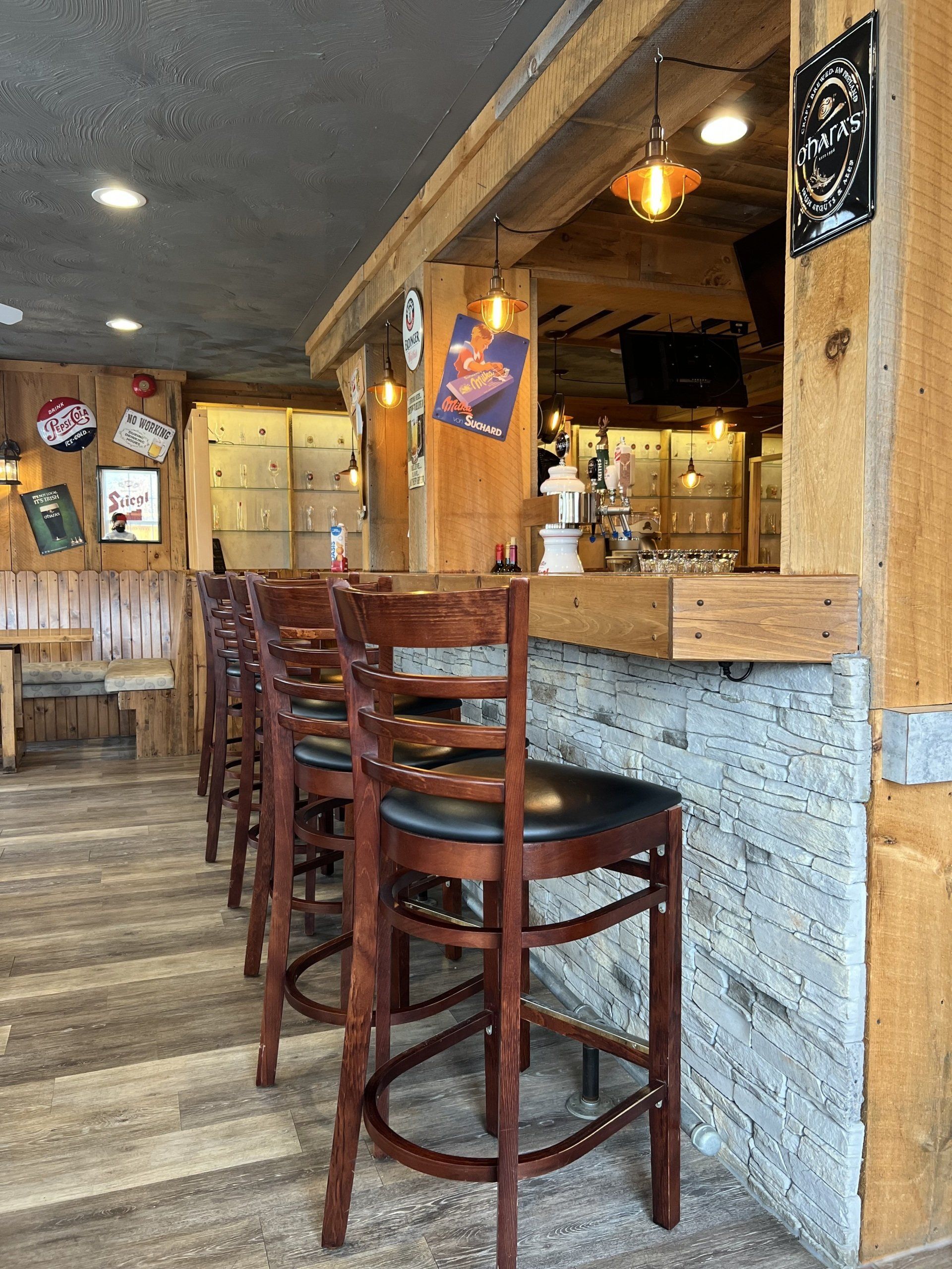 Rustic bar interior with wooden stools, gray counter, and warm hanging lights