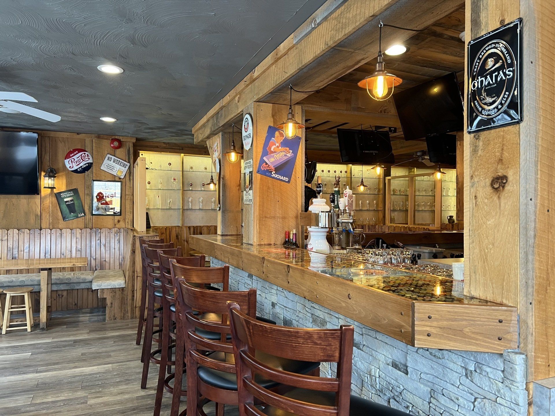 Empty rustic bar interior with wooden stools, stone counter, and warm hanging lights