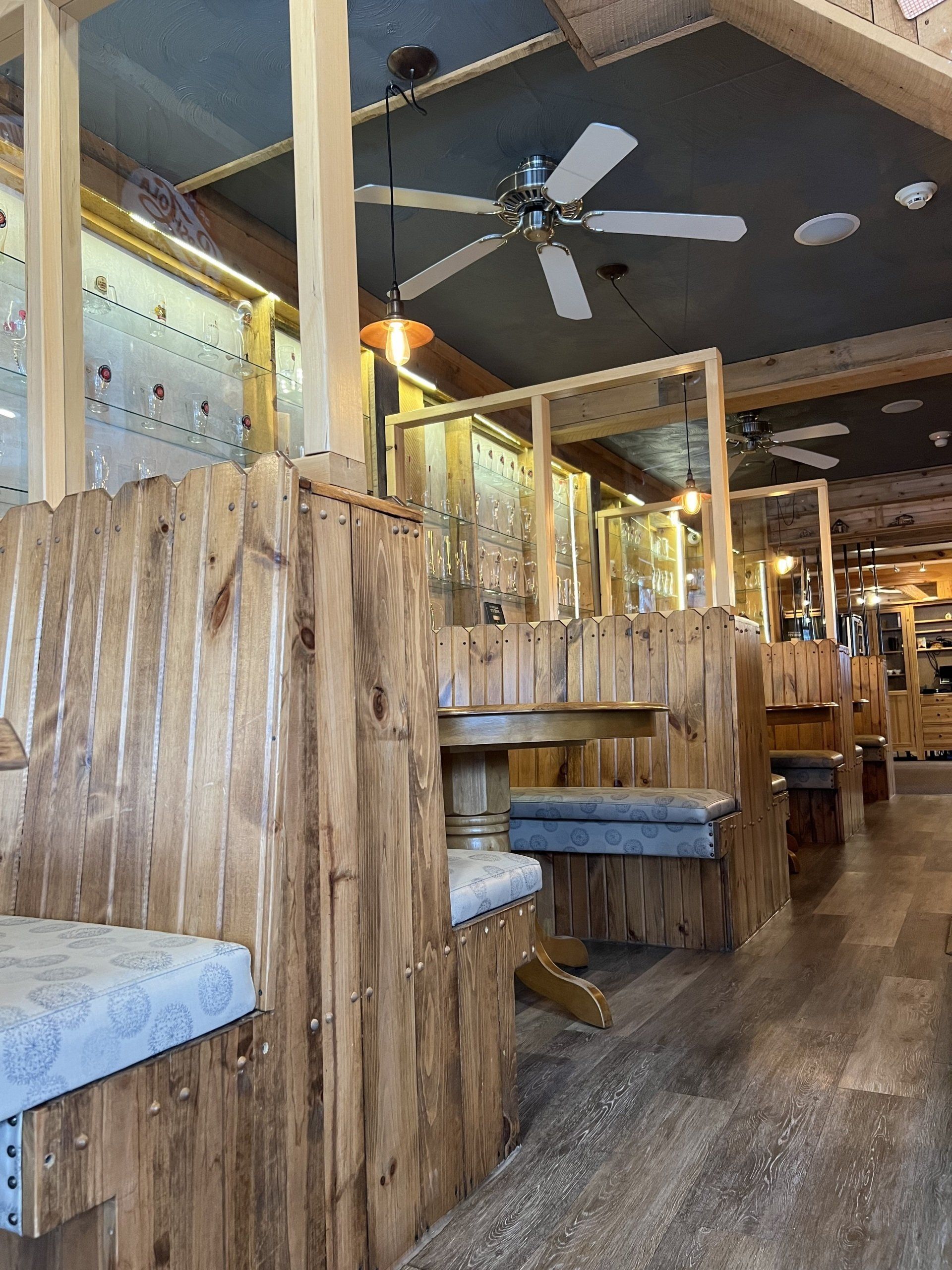 Wooden booth seating in a rustic restaurant interior with ceiling fans and warm lighting
