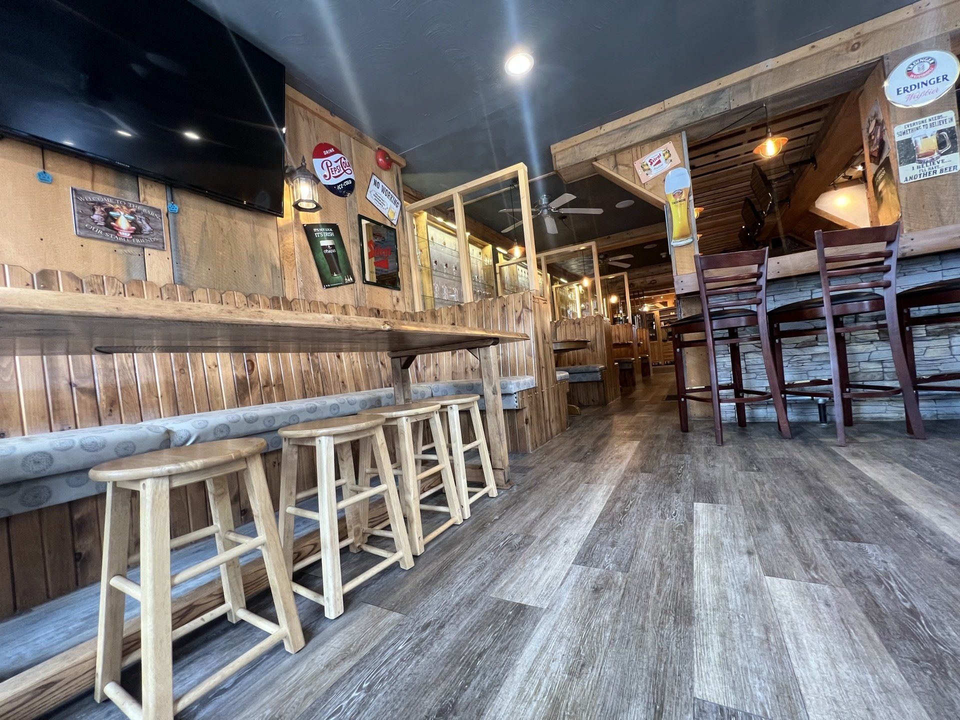 Empty rustic bar interior with wooden stools, long counter, and dim warm lighting