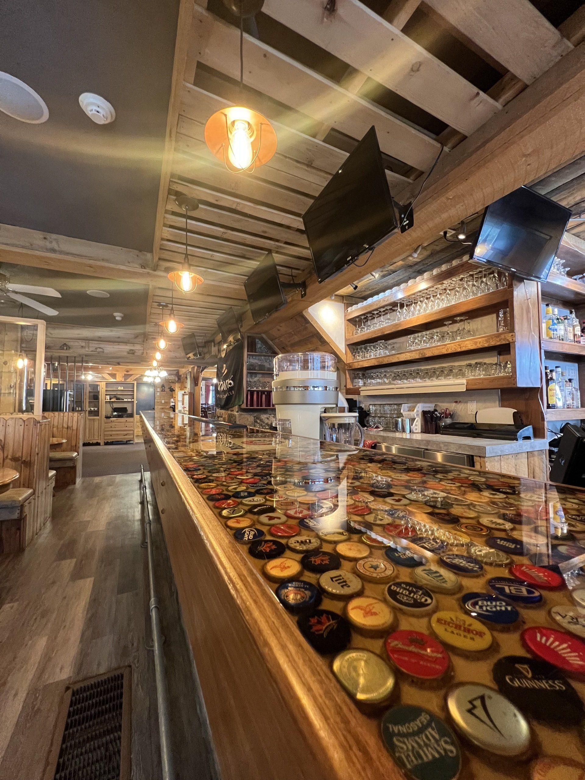 Cozy café interior with long counter, shelves of jars, hanging lights, and open seating area