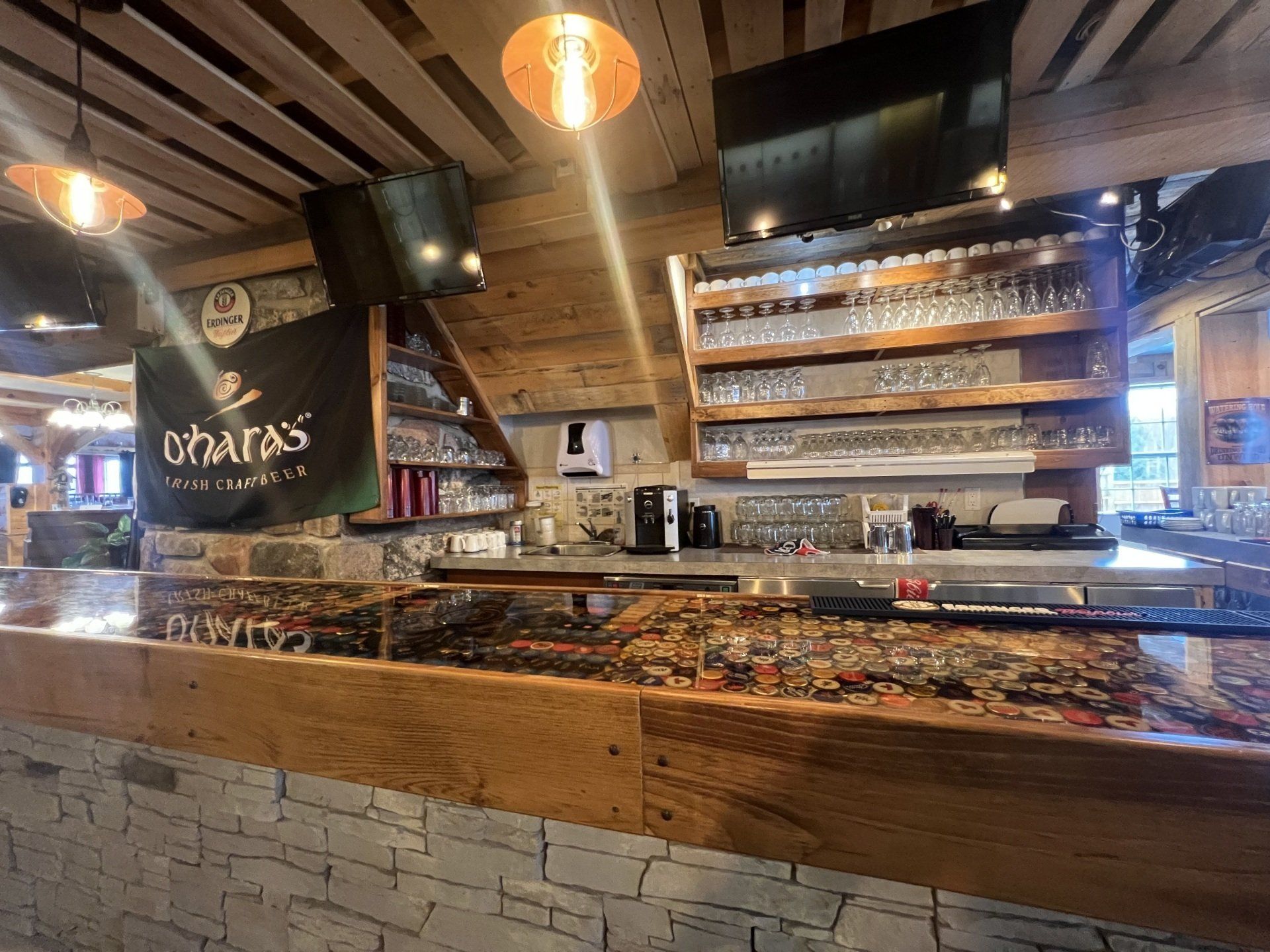 Modern café bar interior with pastries, hanging lights, and shelves of bottles behind the counter