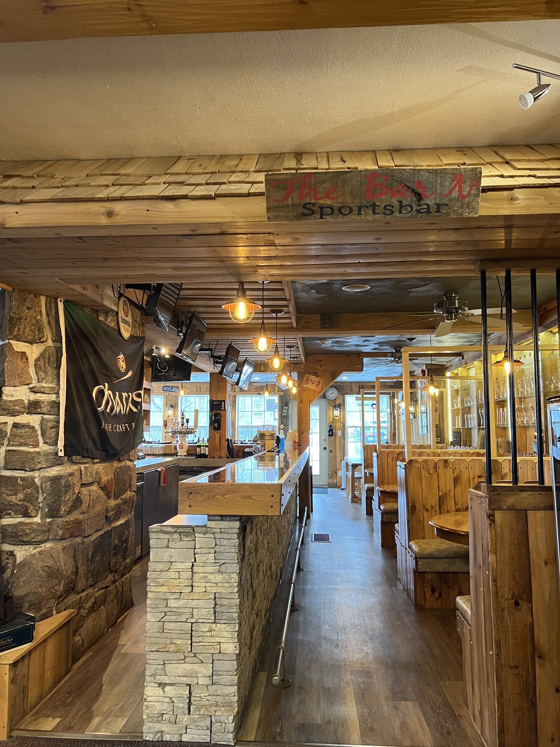 Rustic restaurant interior with wood beams, stone walls, and warm hanging lights.