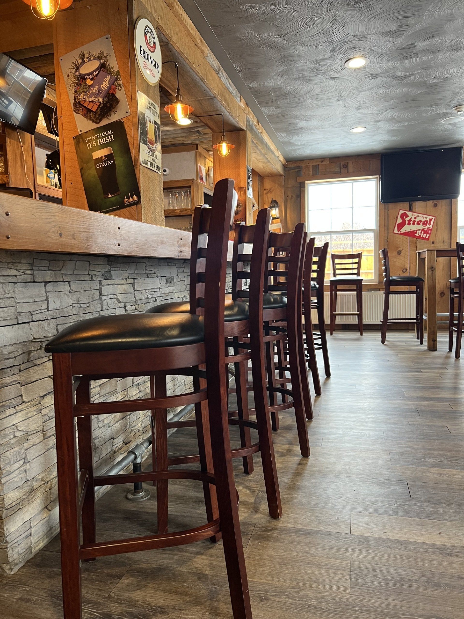 Bar with tall wooden stools lined along a stone counter in a warmly lit restaurant