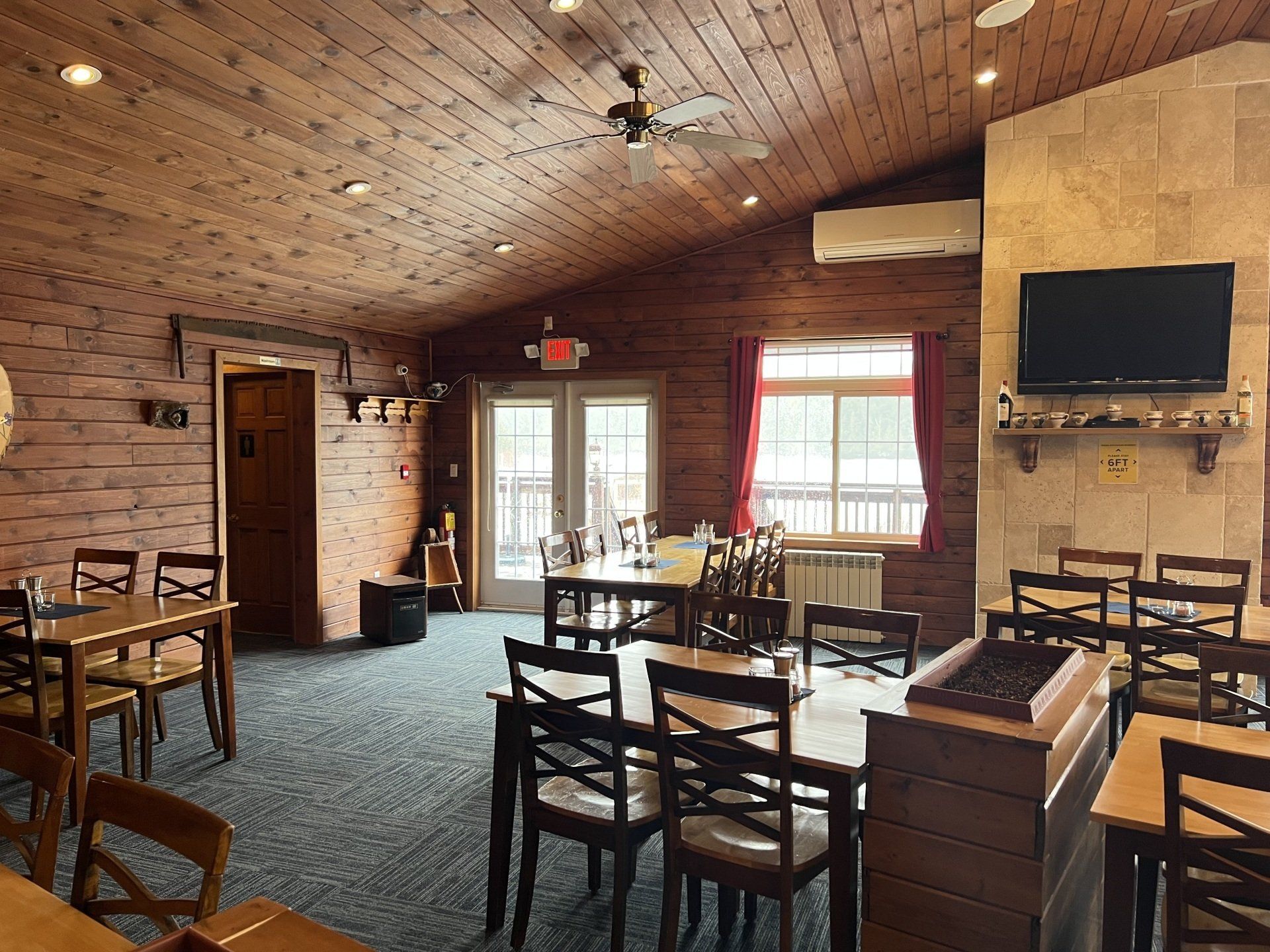 Rustic restaurant dining room with wooden chairs, brick walls, and a wall-mounted TV