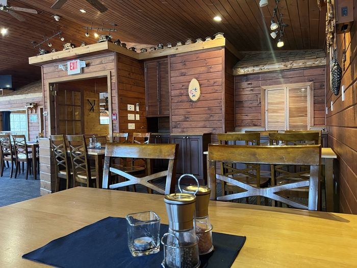 Rustic restaurant interior with wooden booths, tables, and warm ceiling lights