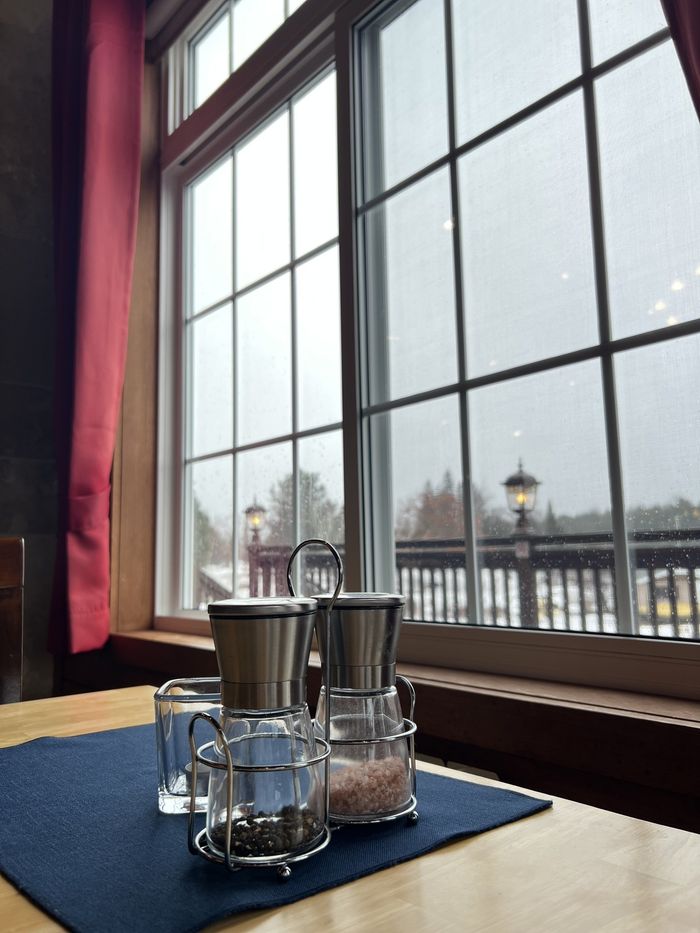 Wine glasses on a blue napkin by a window overlooking a snowy outdoor scene