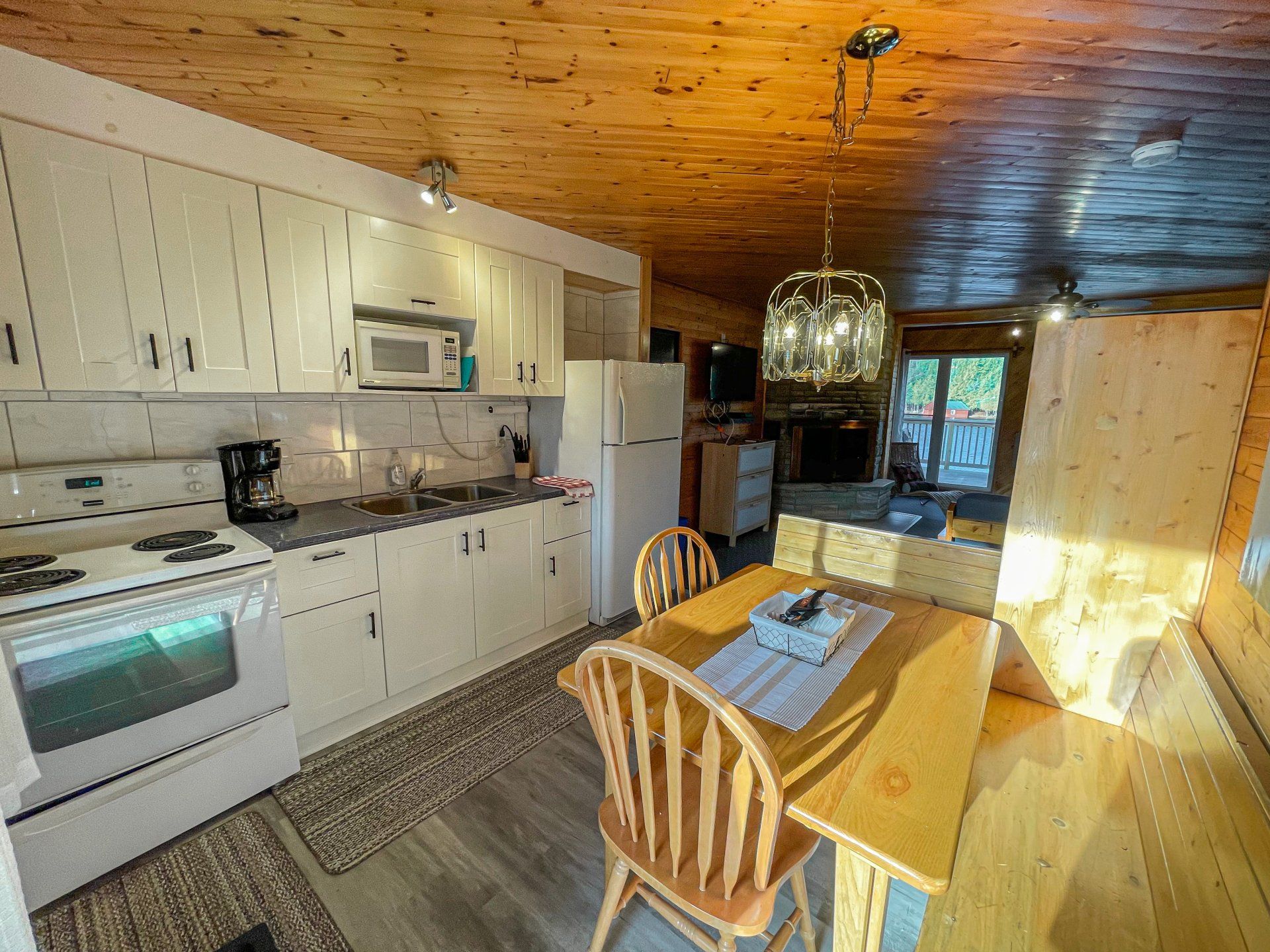 Bright kitchen with white cabinets, wood ceiling, dining table, and sunlight by a window