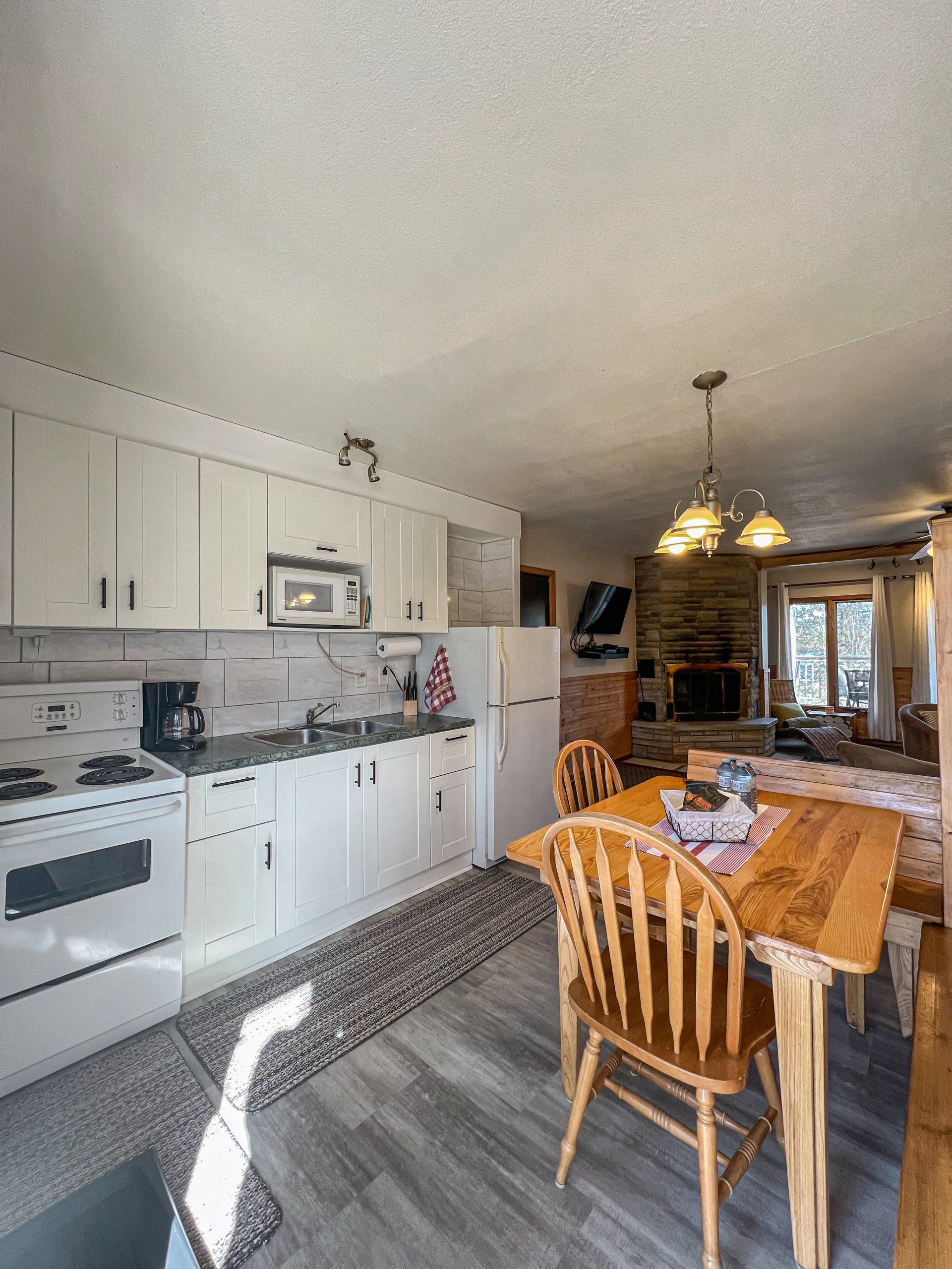 Bright kitchen and dining area with white cabinets, wooden table, and pendant lights