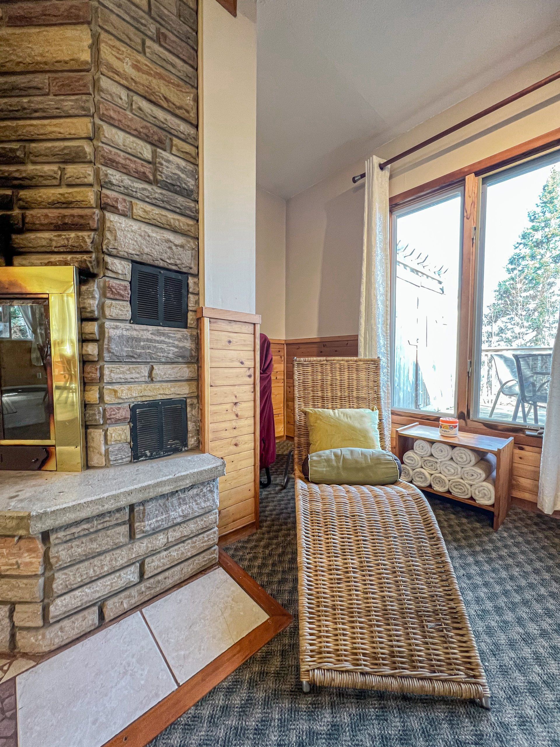 Cozy living room with brick fireplace, wicker chairs, and large sunlit windows
