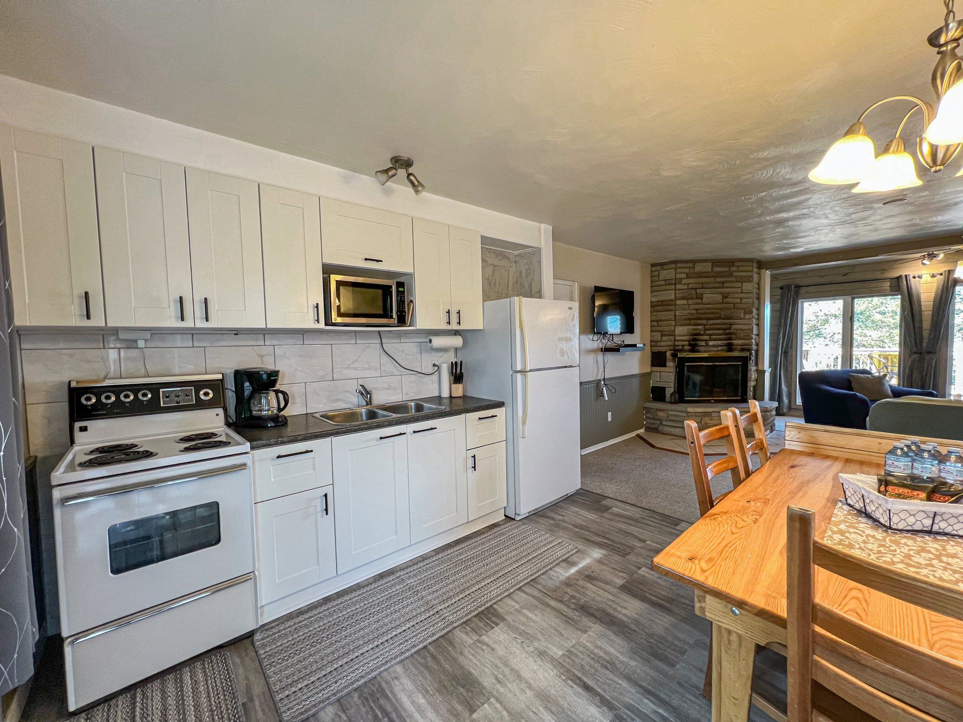 Bright kitchen with white cabinets, stove, refrigerator, and wooden dining table in a home interior