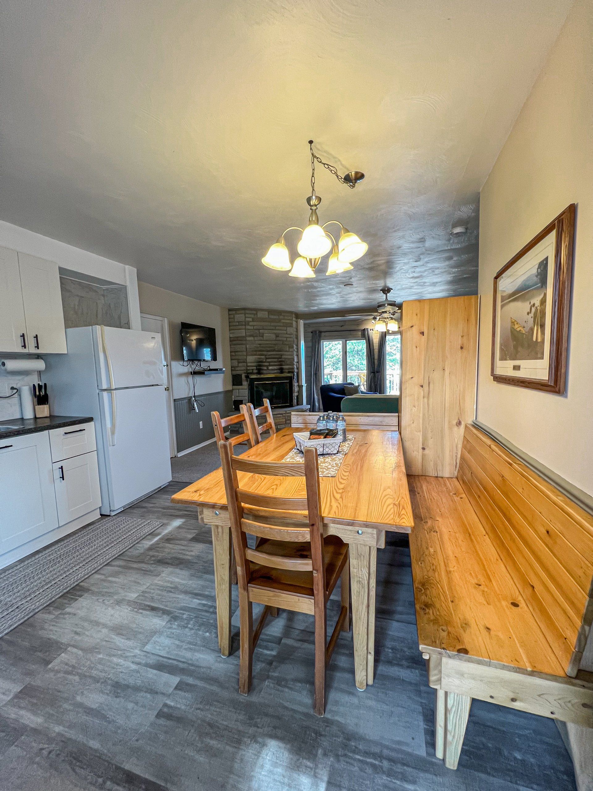 Dining room with wooden table and chairs, white kitchen cabinets, and a bench along the wall.