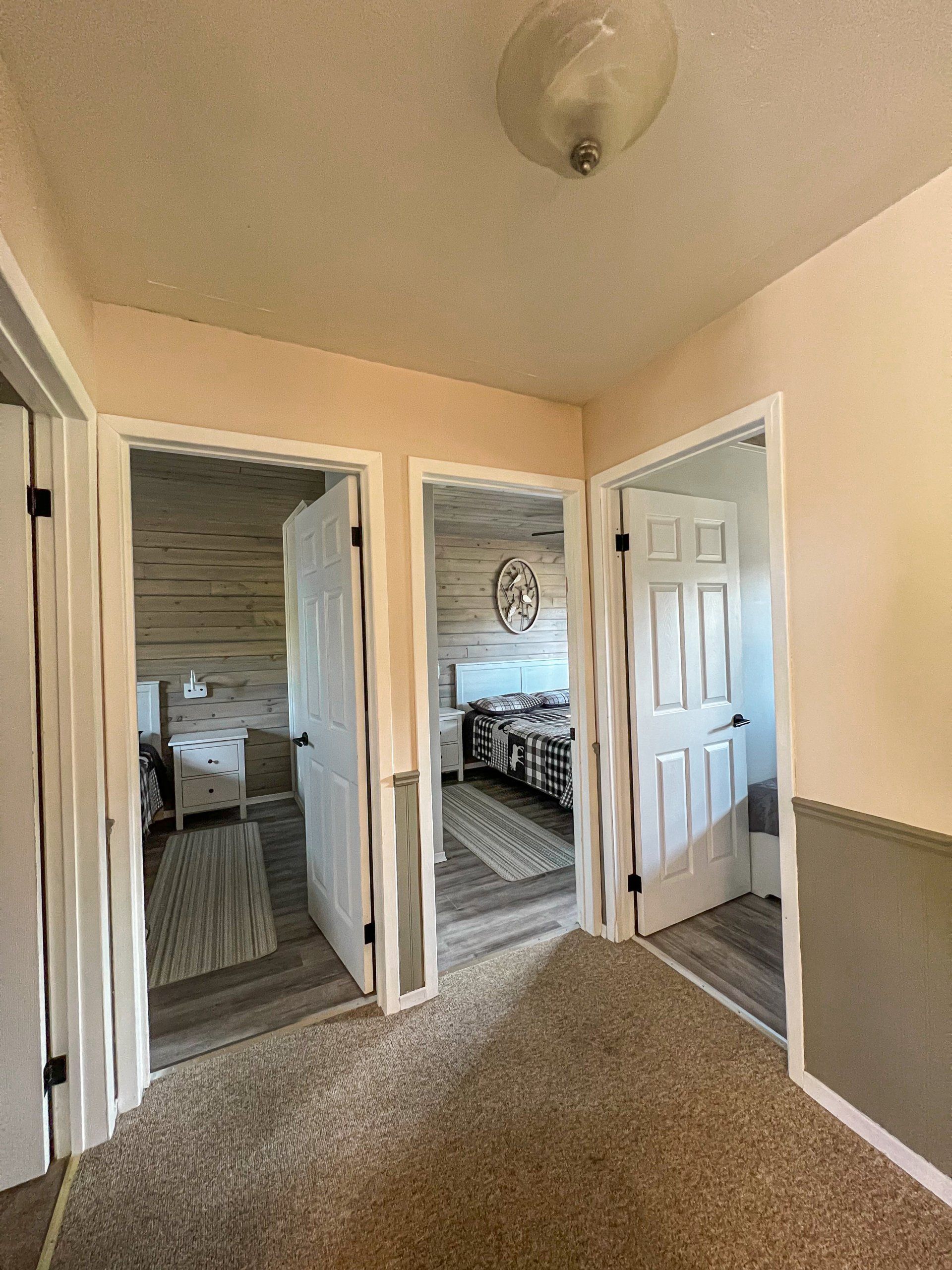 Hallway with open doors, carpeted floor, and bedrooms visible on both sides.