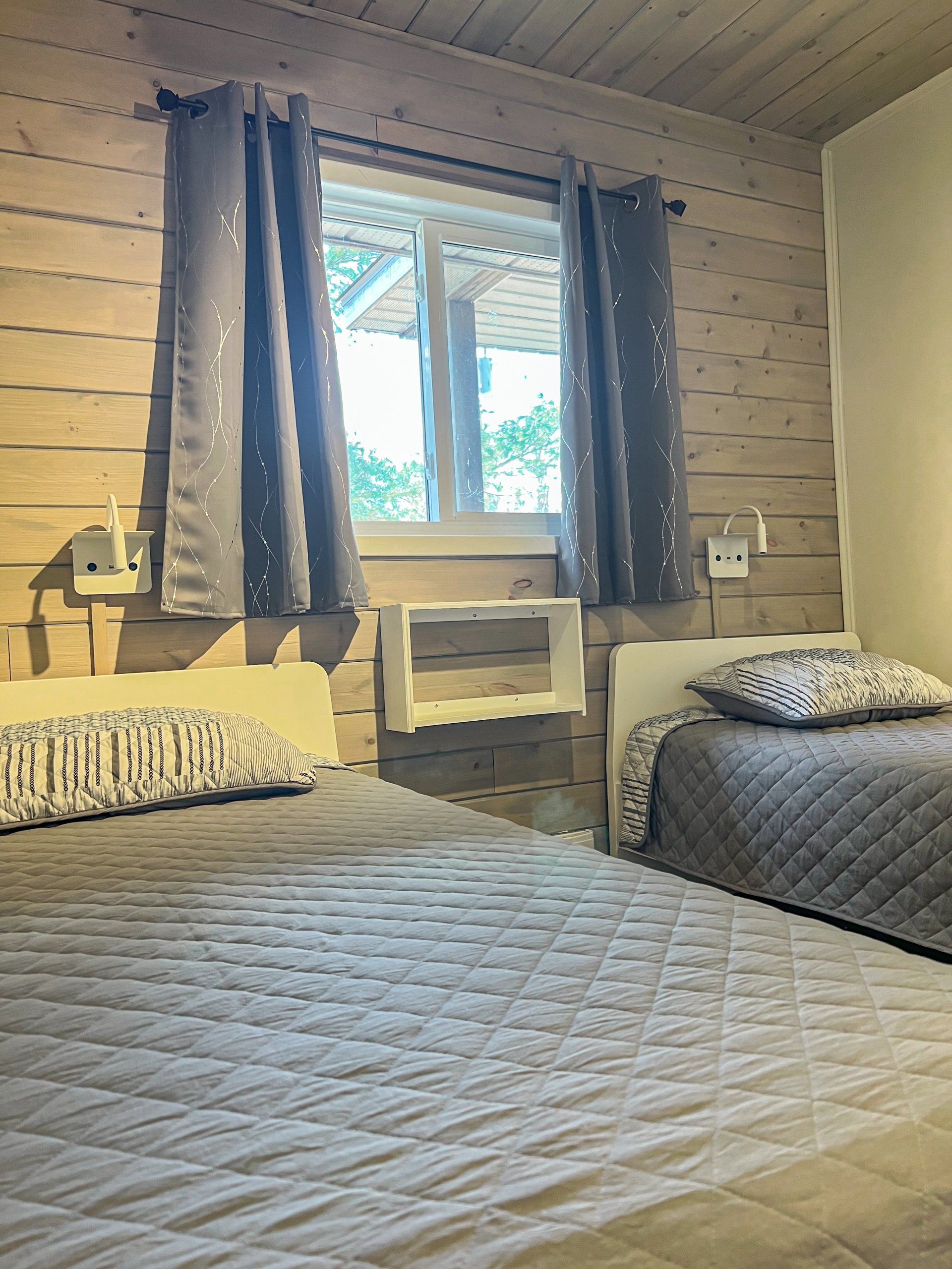 Cozy bedroom with two beds, blue curtains, and a window between them