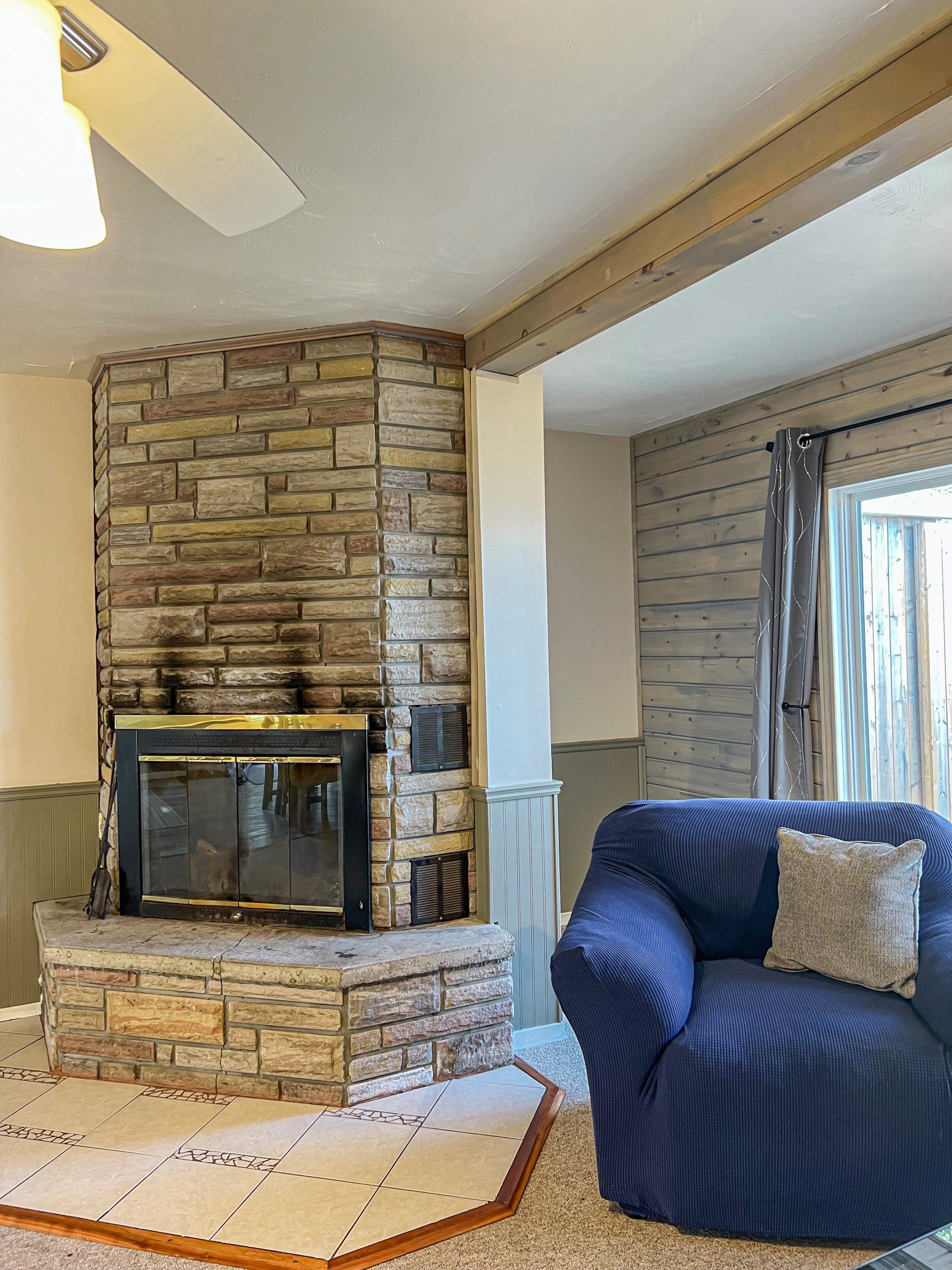 Cozy living room with a stone fireplace and dark blue upholstered armchair