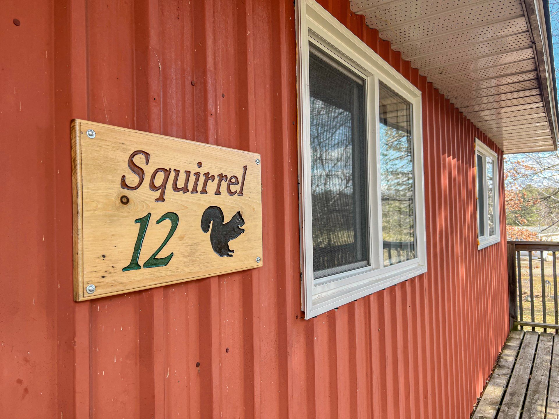 Squirrel 12 sign on a red corrugated wall beside windows and a porch roof