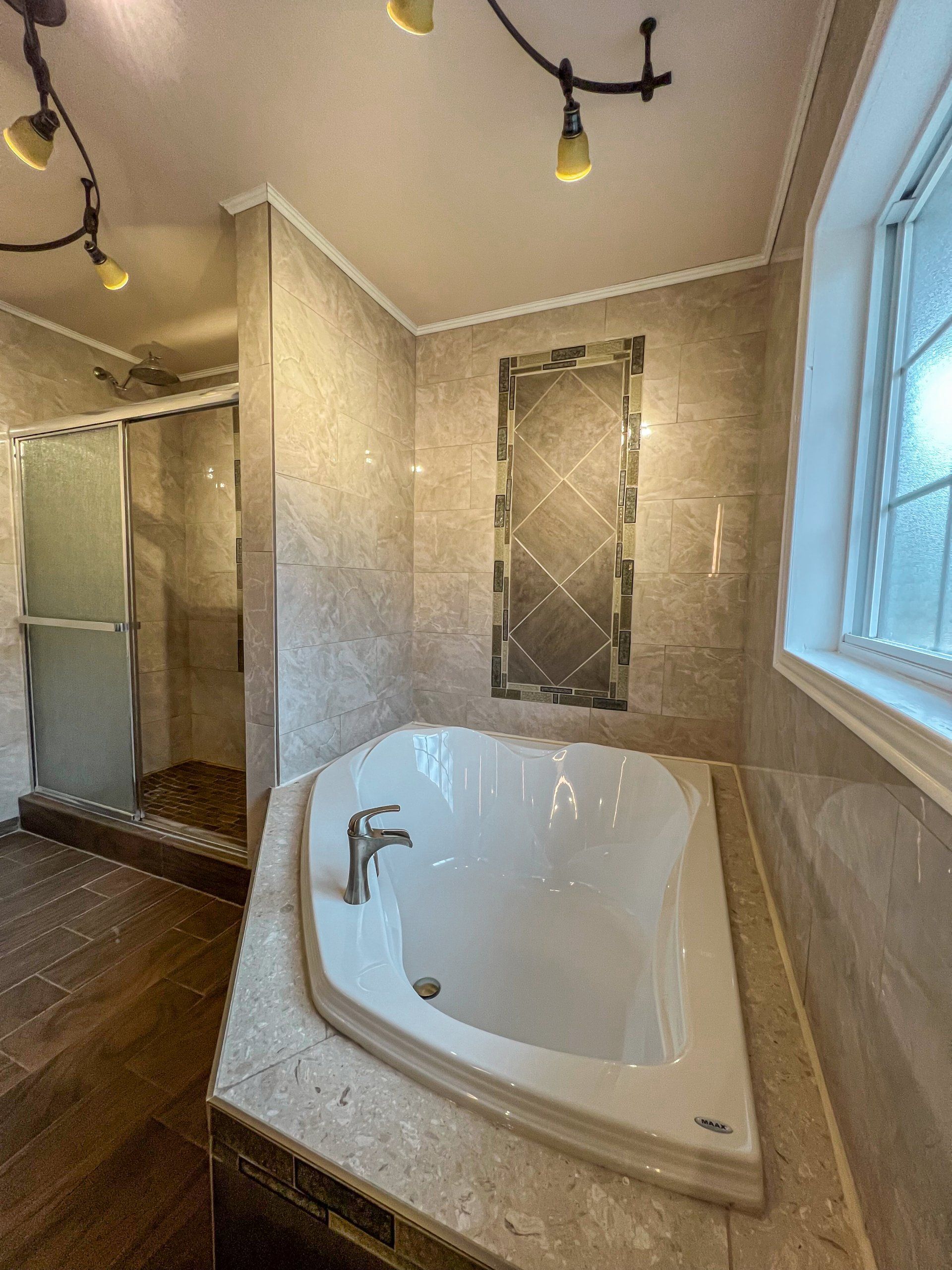 Bathroom with corner soaking tub, tiled shower, and large window with dark wood floor