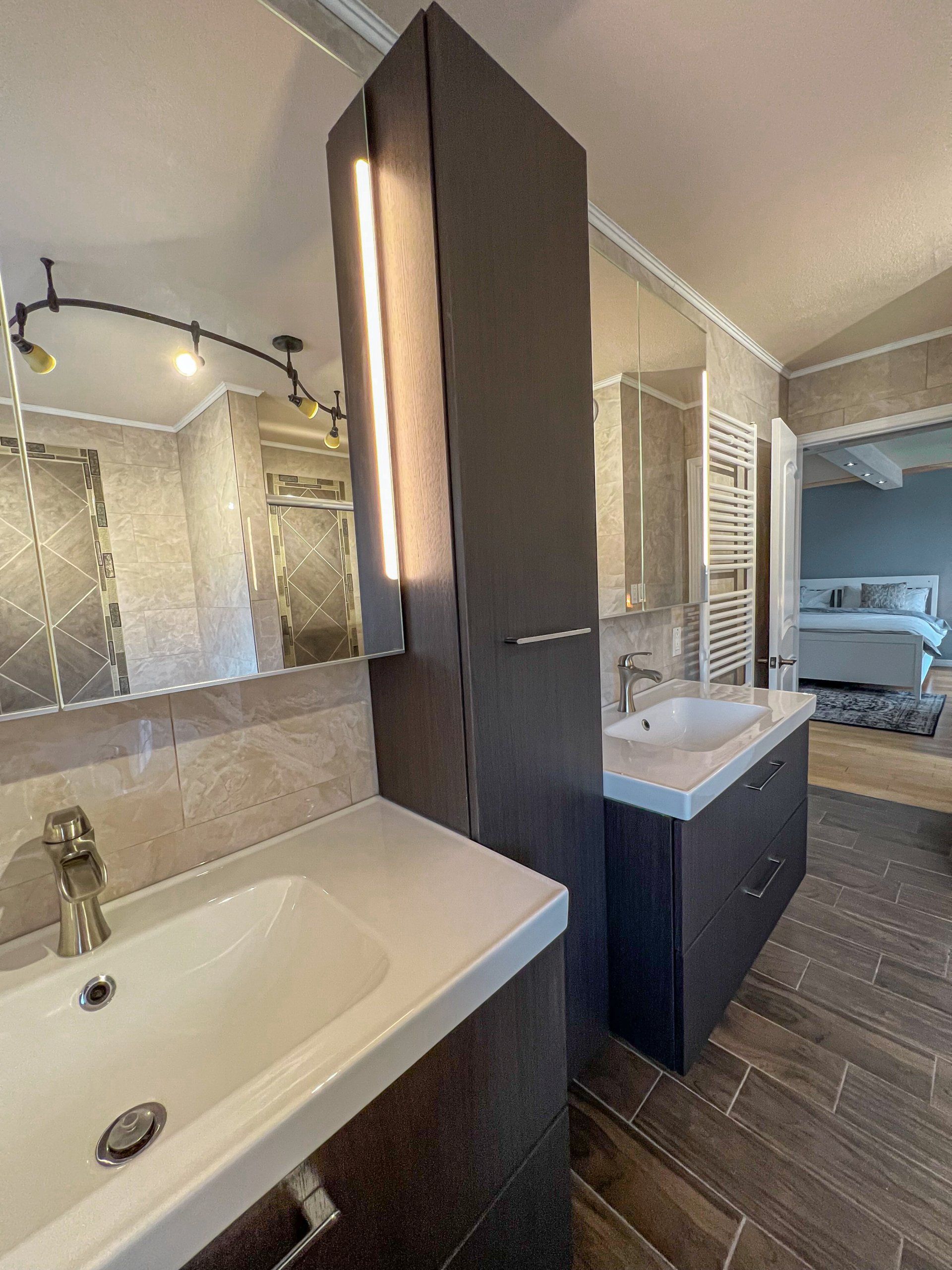 Modern bathroom with double sinks, dark cabinetry, large mirror, and walk-in shower.