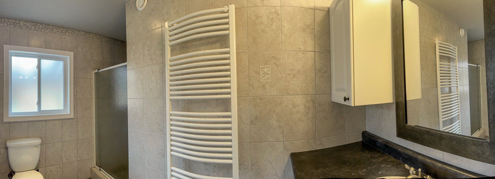 Bathroom with beige walls, white towel warmers, small window, and a vanity mirror with sink.