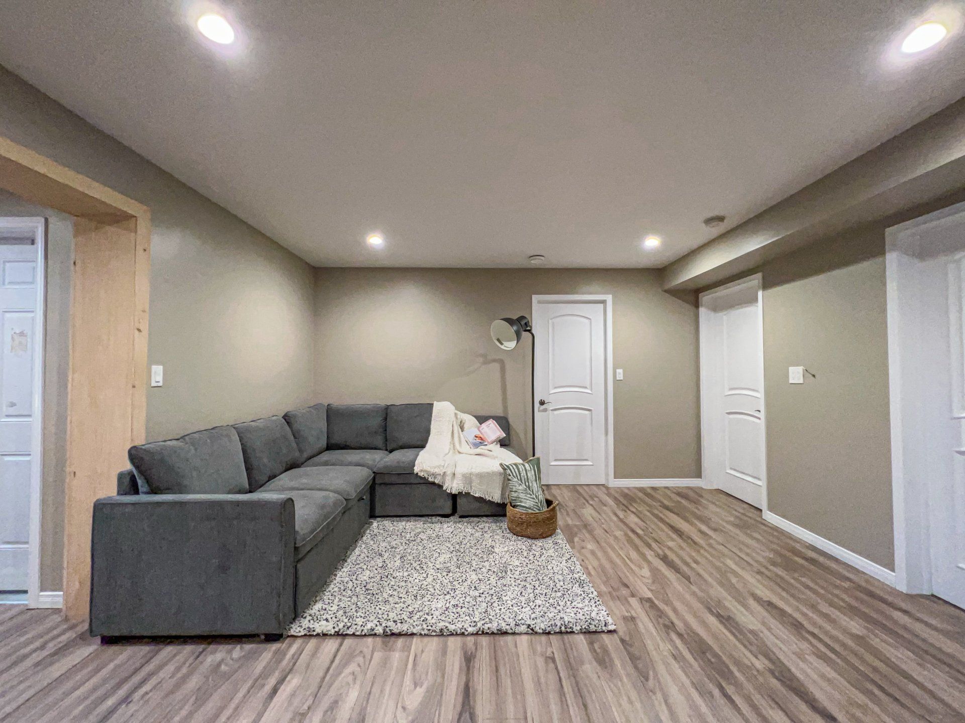 Modern living room with gray sectional sofa, patterned rug, wood floors, and recessed ceiling lights