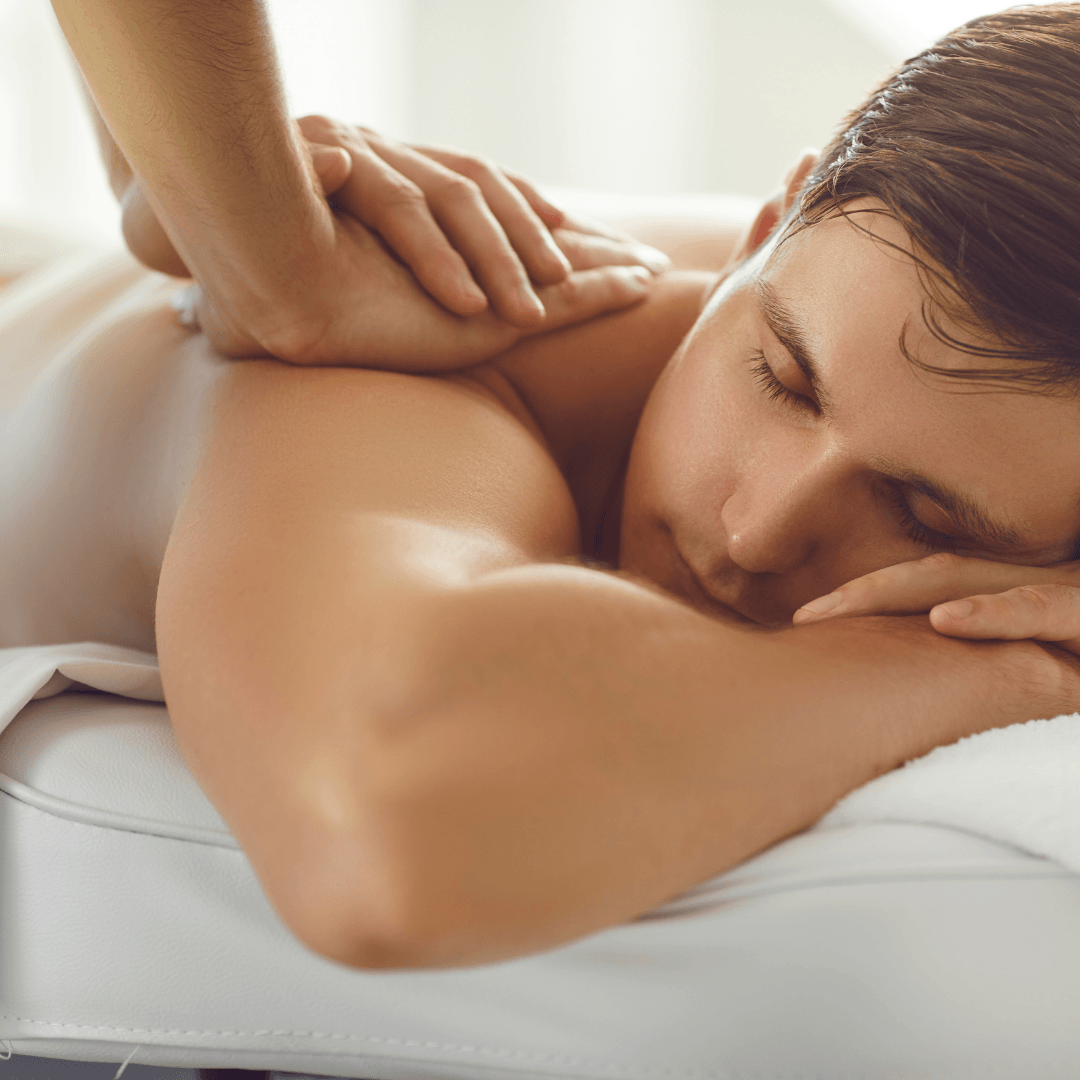 A man is laying on a bed getting a massage