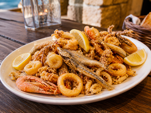 Piatto di frutti di mare fritti con spicchi di limone su un tavolo di legno.