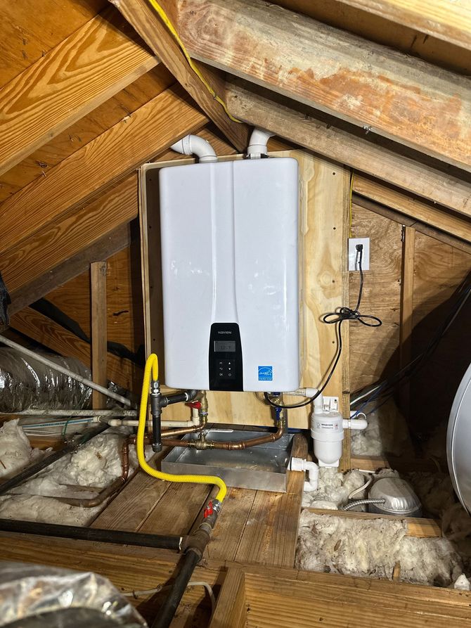 Wall-mounted white water heater in an attic with exposed ducts and plumbing pipes.