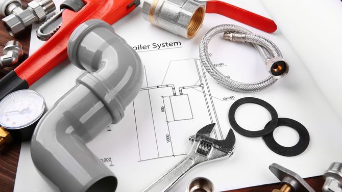 Plumbing tools and fittings on a blueprint, including a wrench, pipe, tape measure, and drain parts