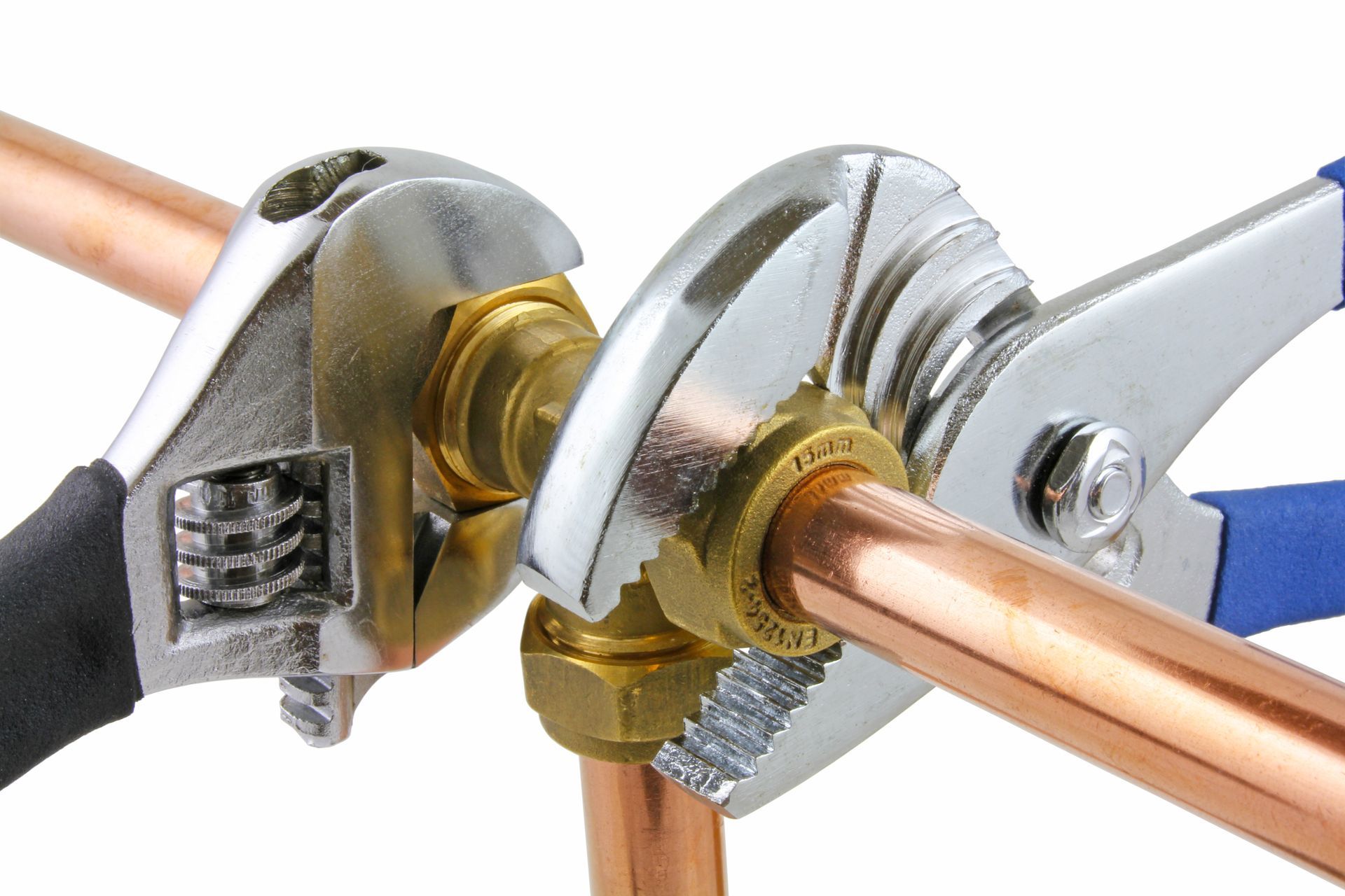 Two adjustable wrenches tightening a brass fitting on a copper pipe
