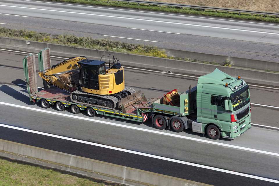 excavator machines being transported on a flatbed truck on a highway