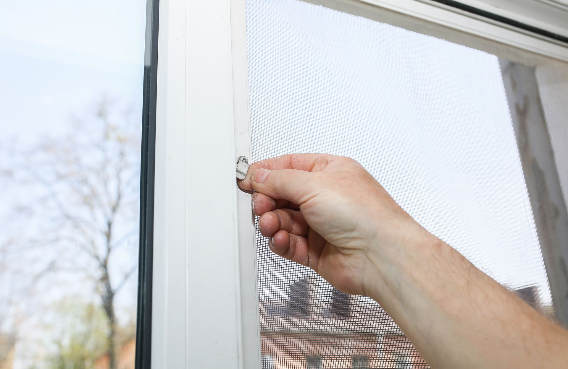 Hand opening a screen window latch.