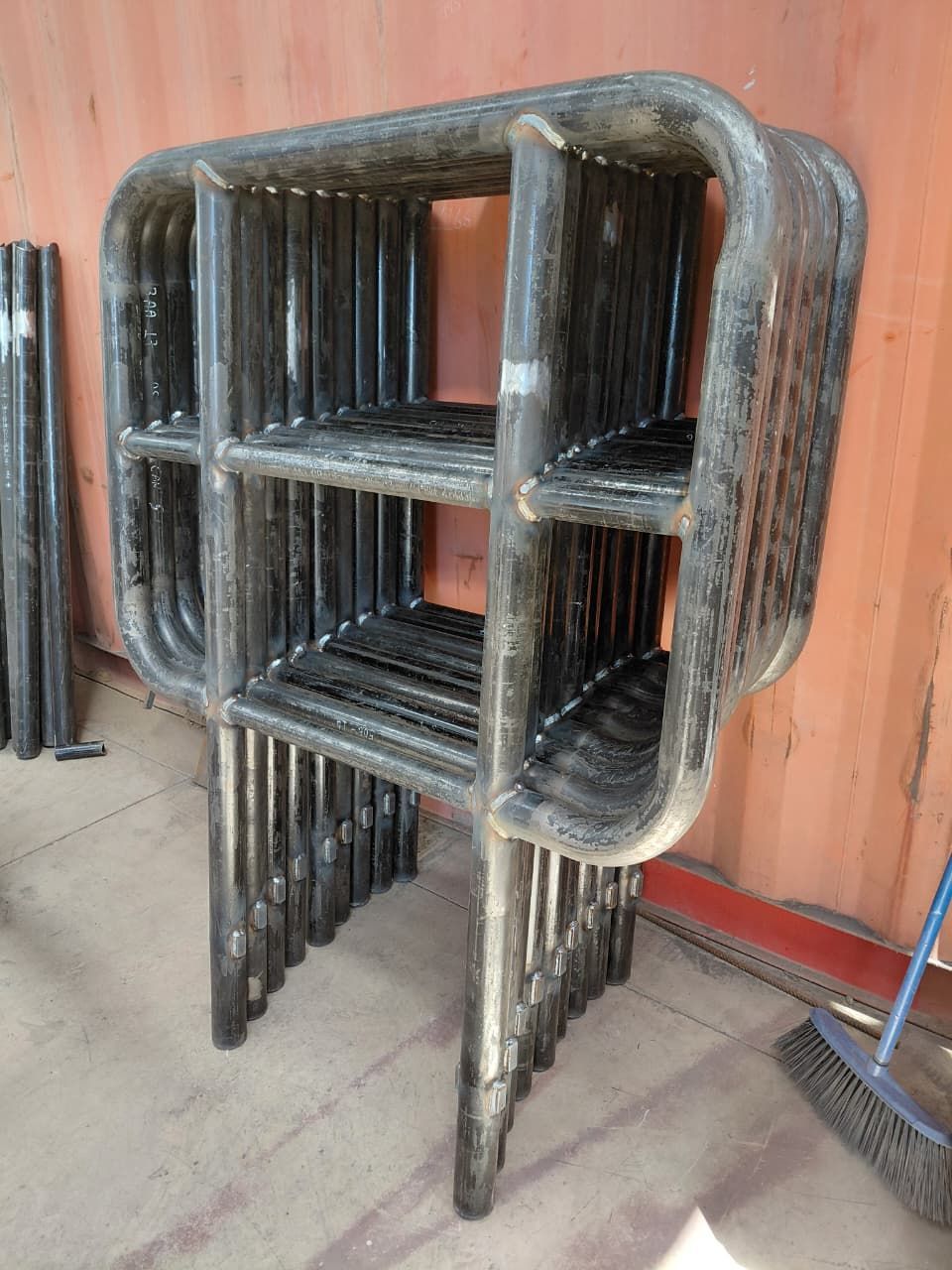 Marco de andamio metálico, de color gris, con soportes horizontales, colocado dentro de un contenedor.