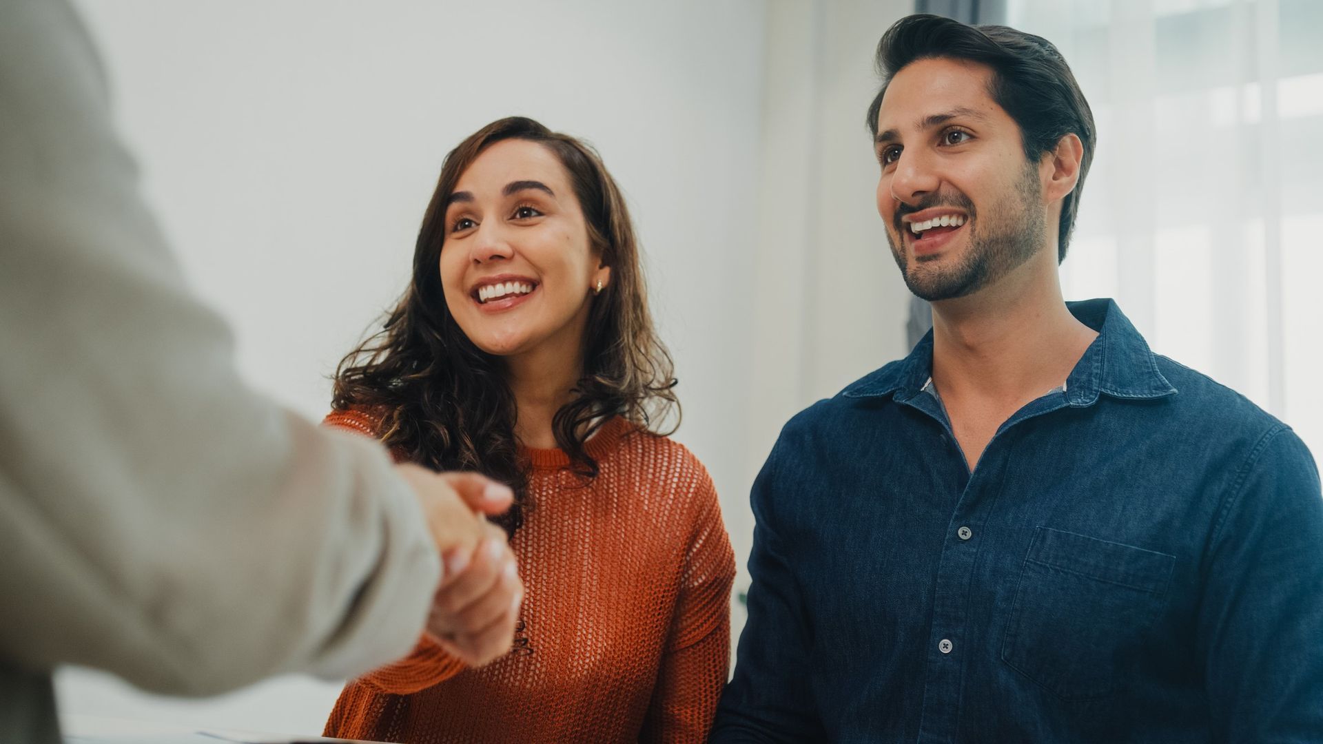 A man and a woman are shaking hands with a real estate agent. A man and a woman are shaking hands with a real estate agent.