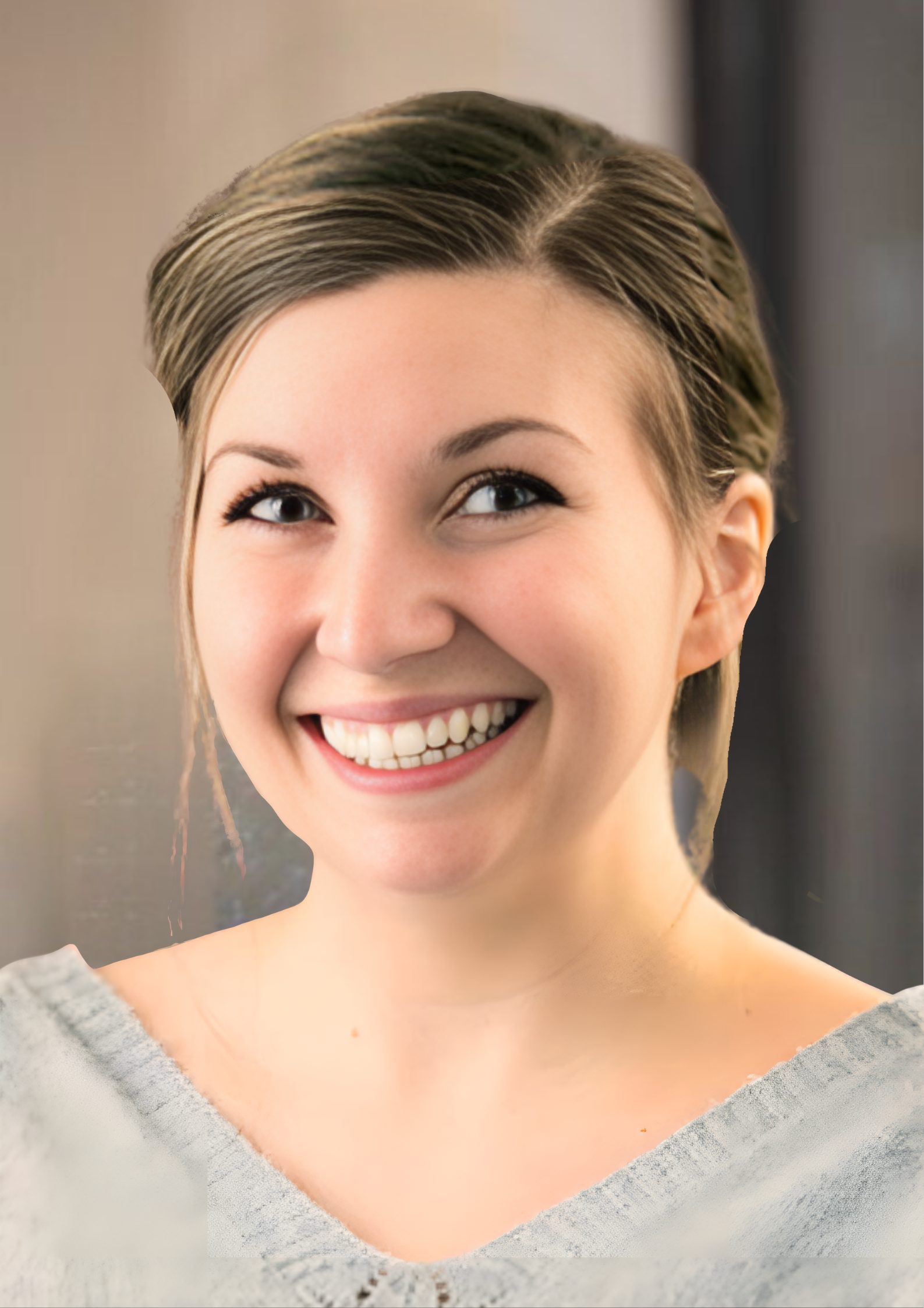 Smiling woman with hair pulled back, wearing a light gray top, against a softly blurred background