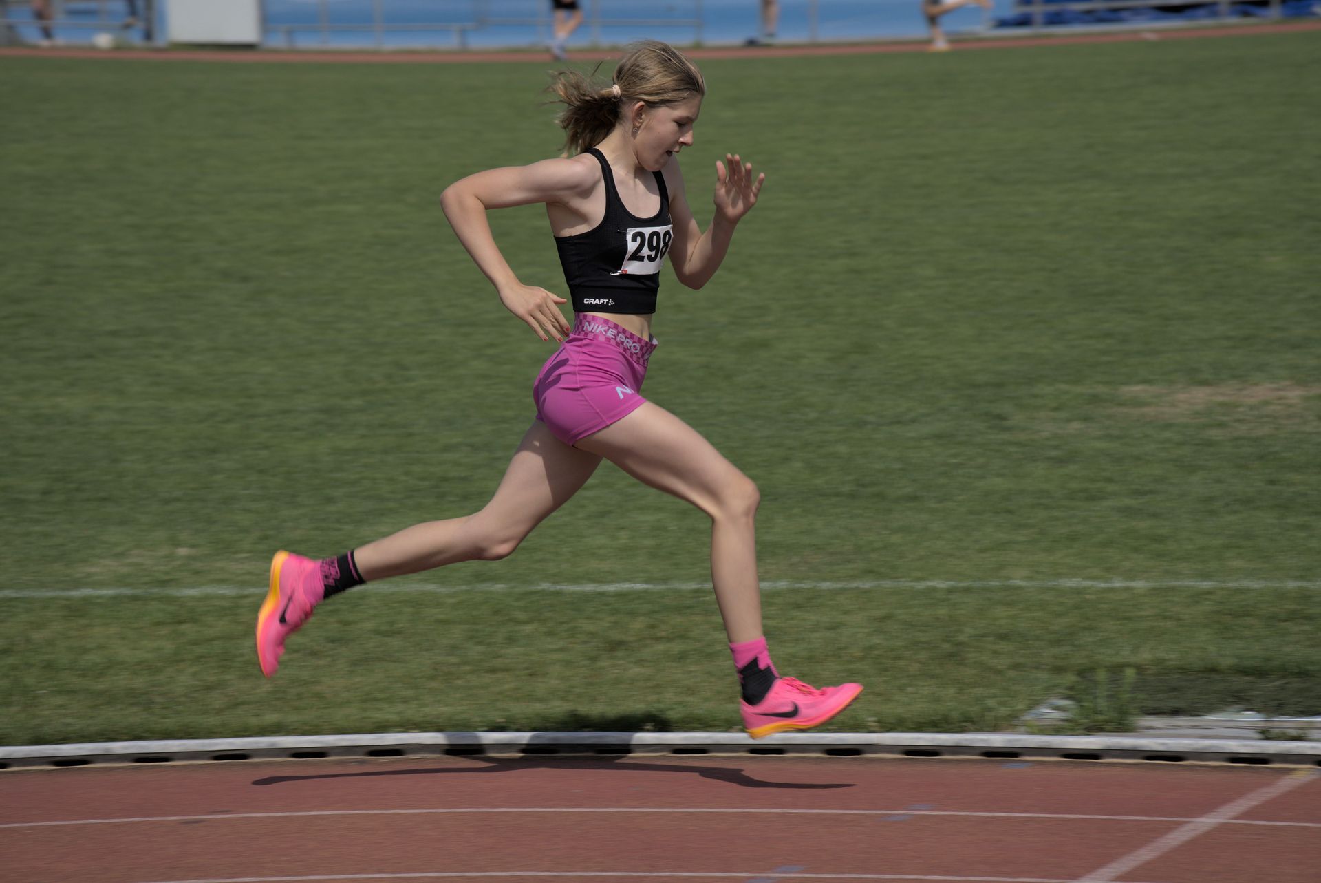 Track runner in black and pink sprinting on a track during a race