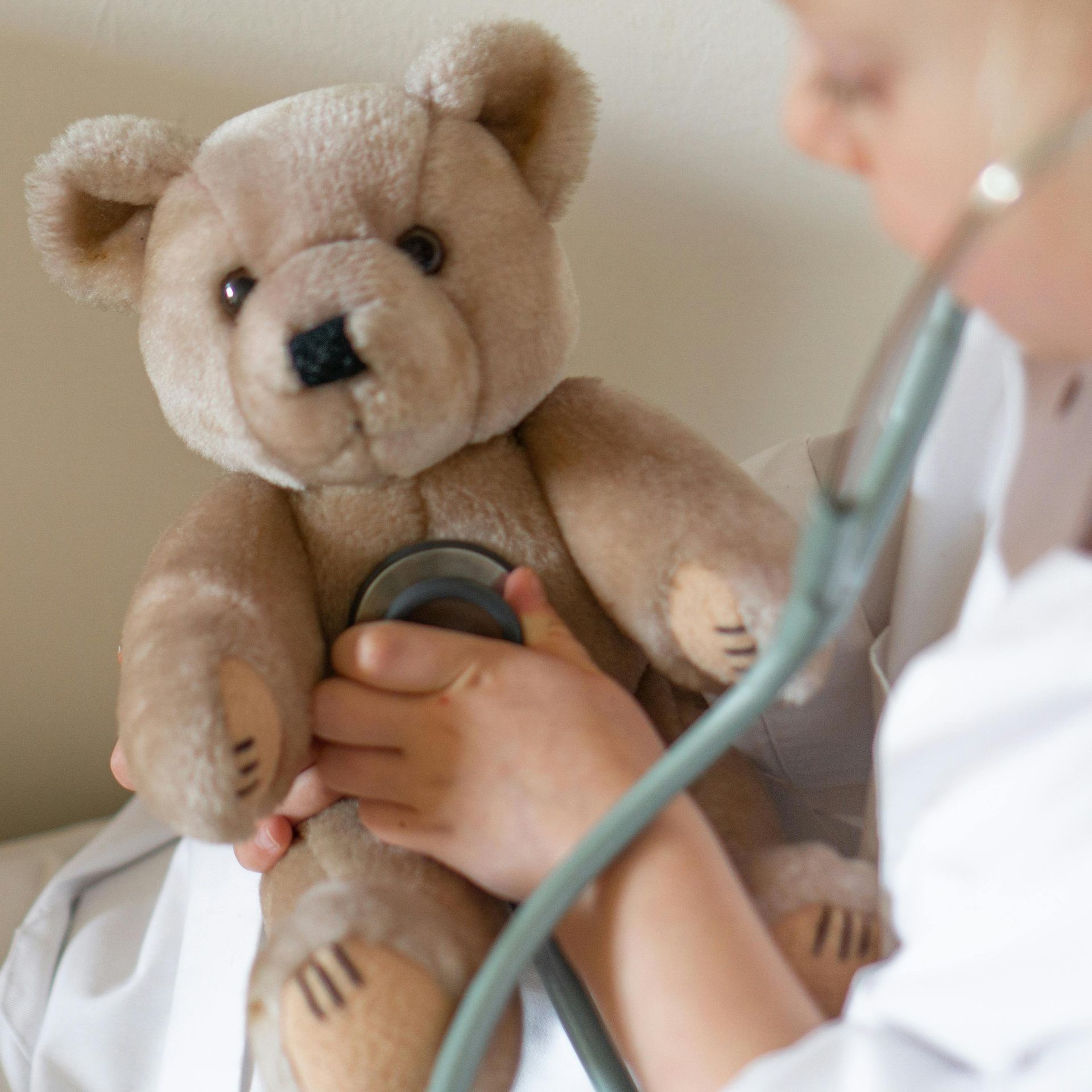 Doctor using a stethoscope to examine a teddy bear patient