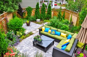 Outdoor patio with lime green sectional, black coffee table, and colorful cushions in a lush garden courtyard