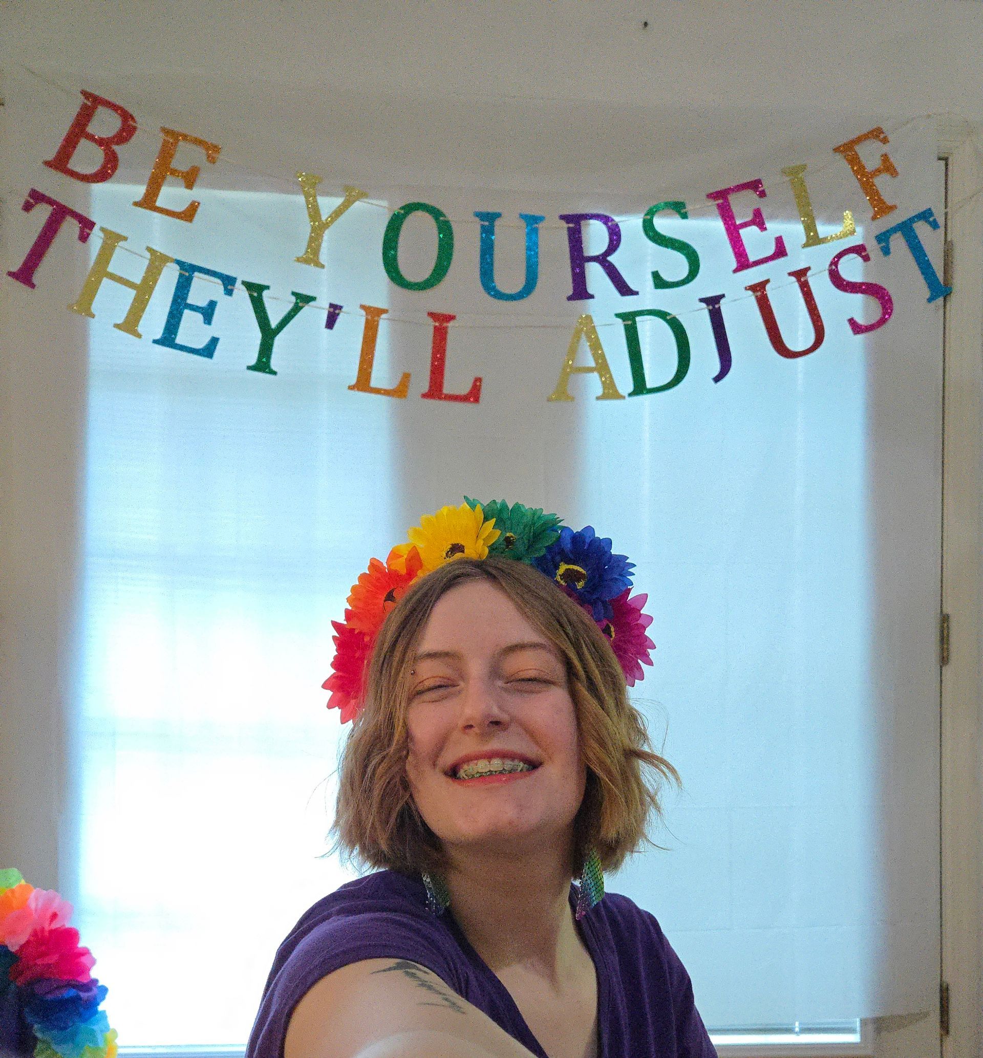 A person is smiling in front of a banner that says be yourself they 'll adjust