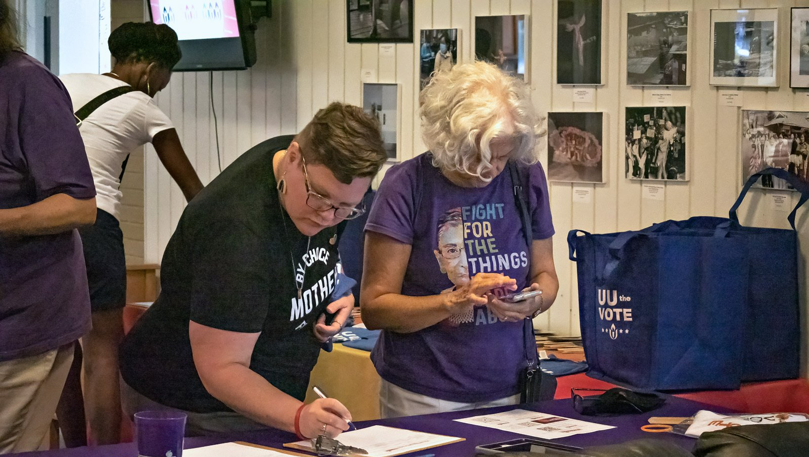 A group of people are standing around a table, filling out forms