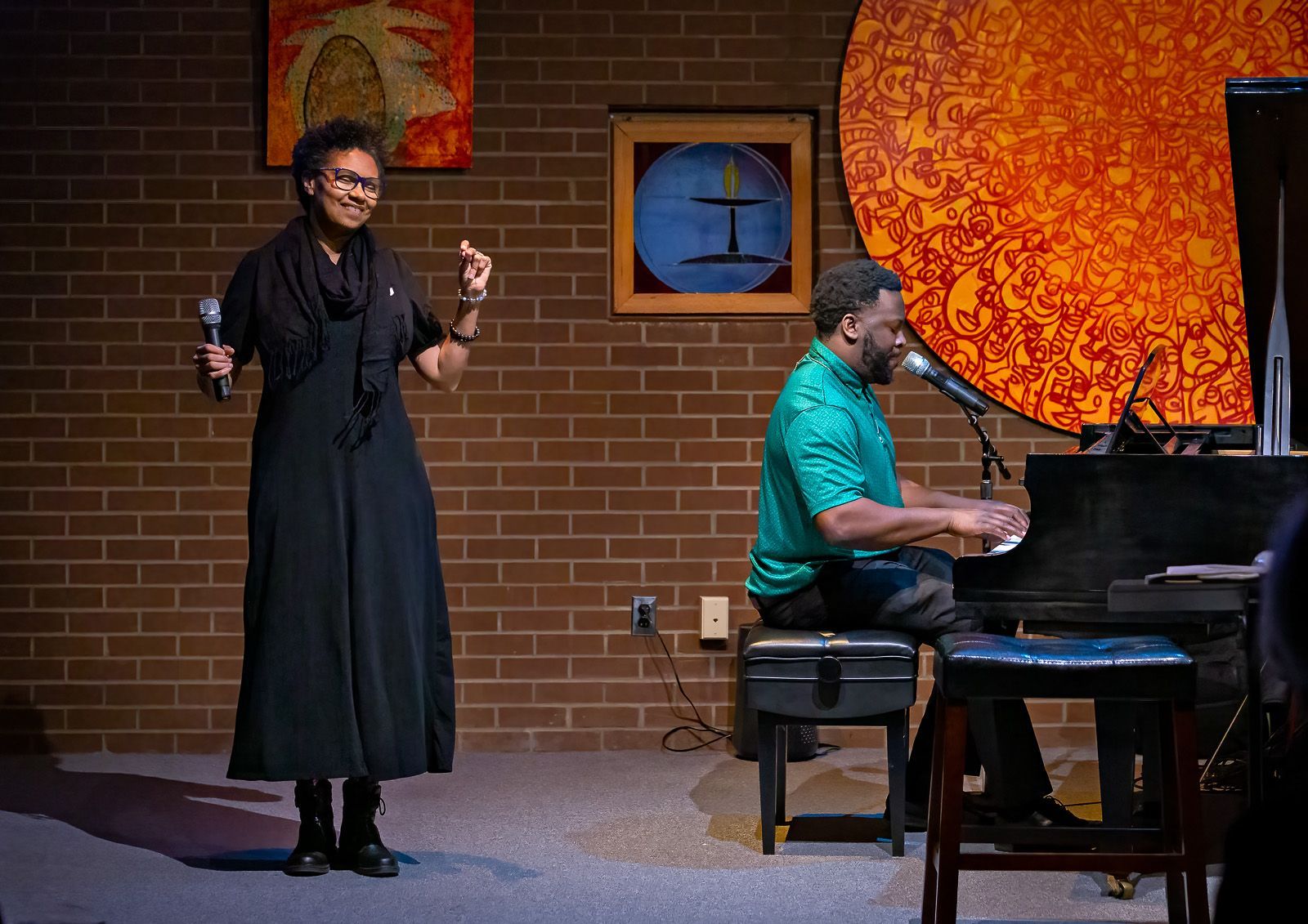 A man is playing a piano while a woman sings on stage.