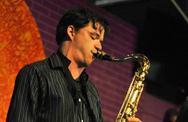 A man in a striped shirt is playing a saxophone
