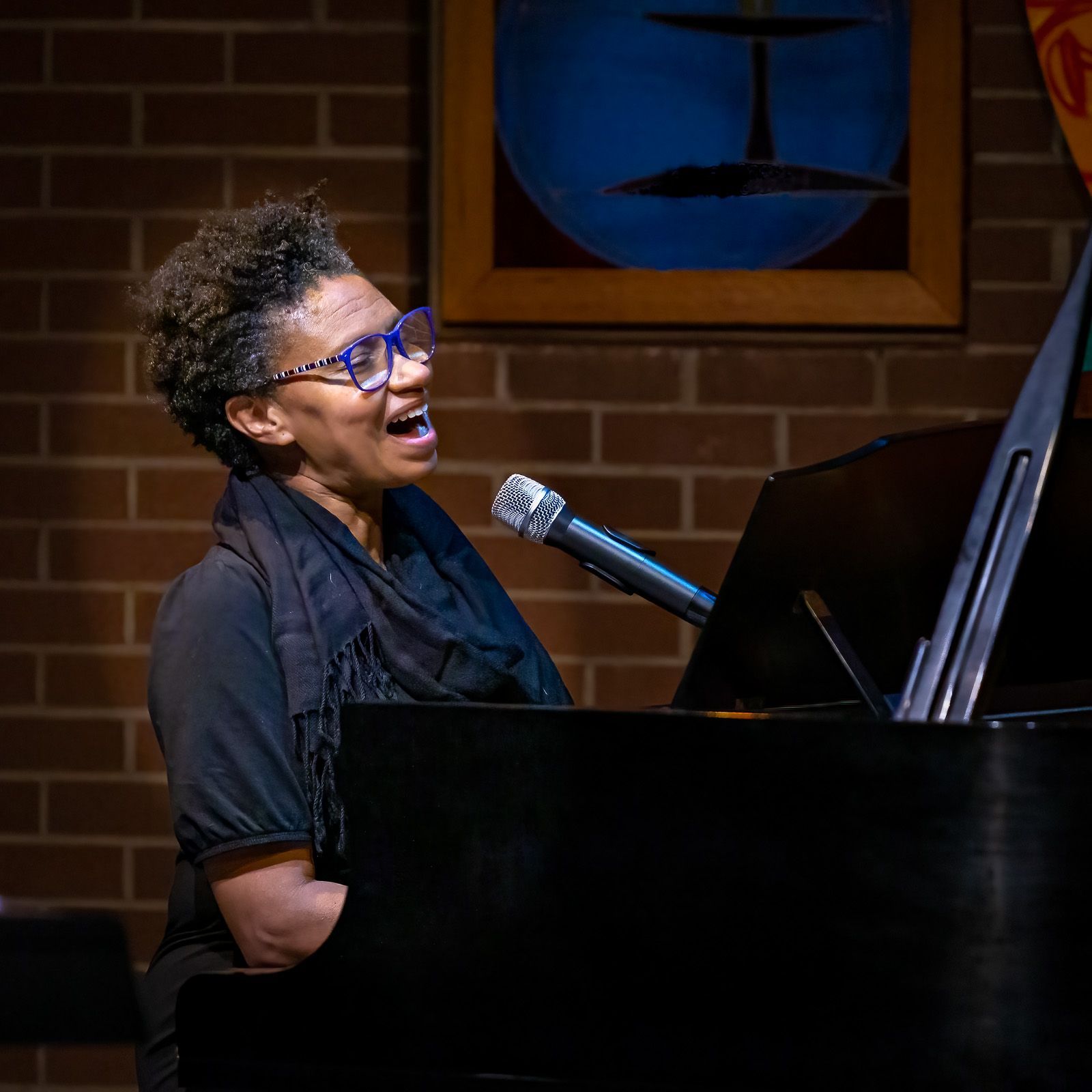 A woman singing into a microphone while playing a piano