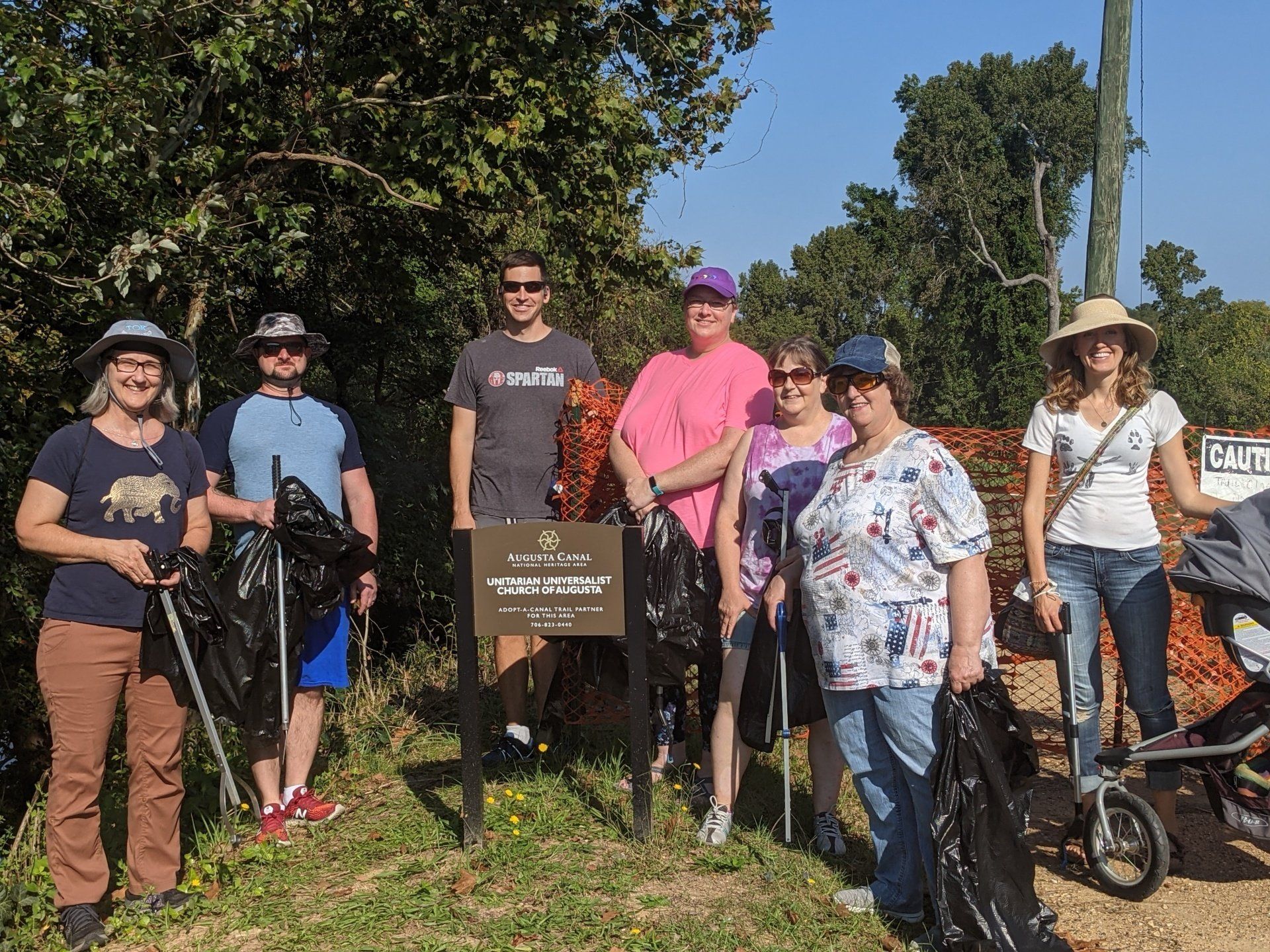 A group of people are standing in a field holding trash bags.