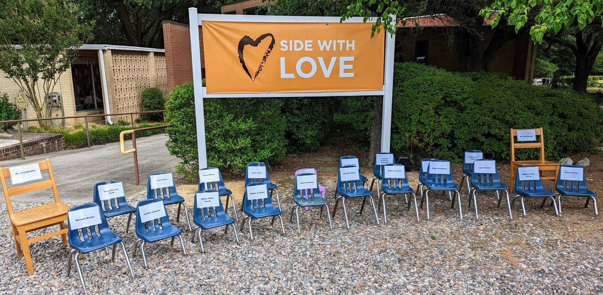 A row of empty chairs are lined up under a sign that says side with love.