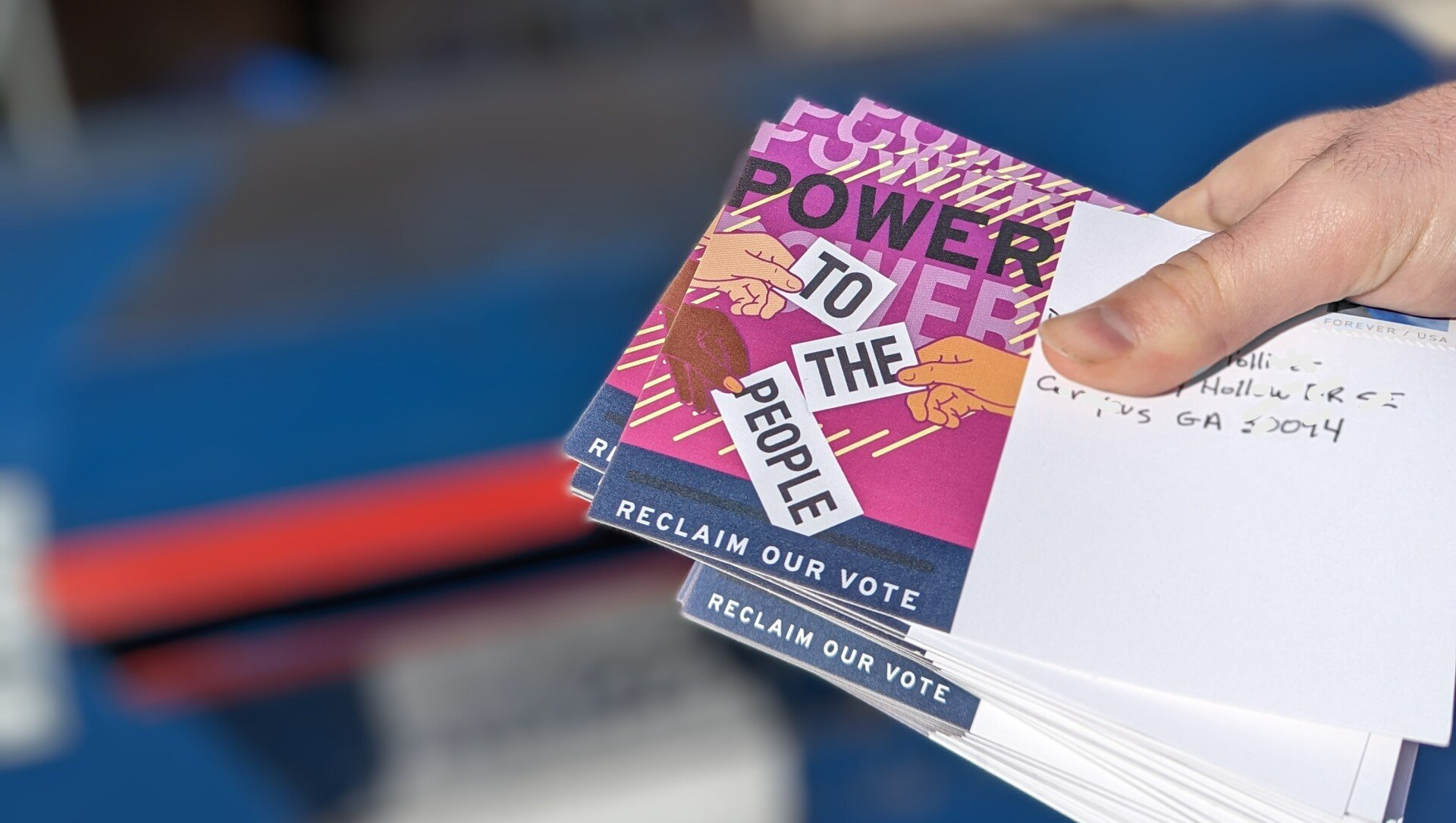 A person is holding a stack of postcards that say power to the people.
