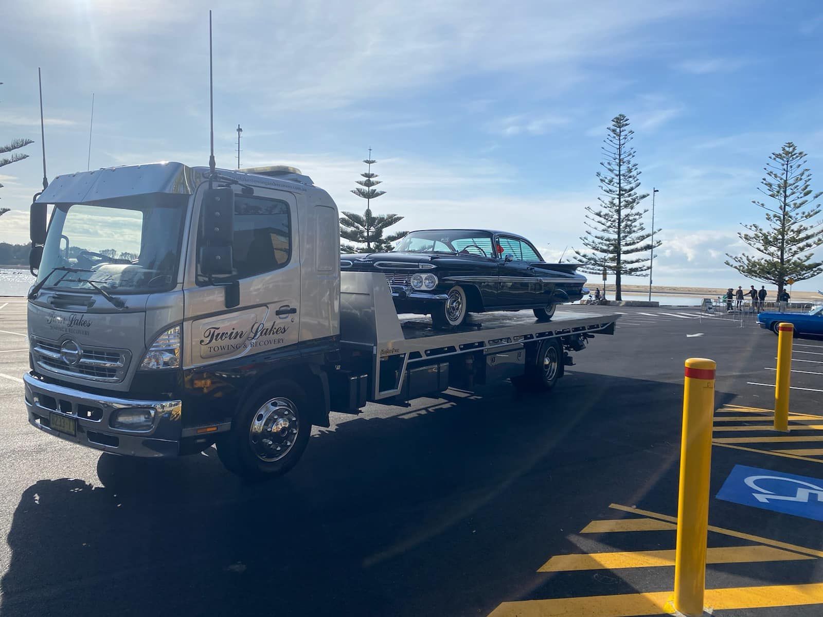 A Tow Truck Is Towing a Car in A Parking Lot — Twin Lakes Towing & Recovery in Cardiff, NSW