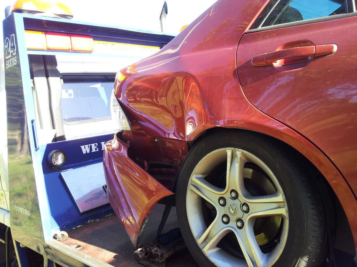 A Red Car Is Being Towed by A Tow Truck — Twin Lakes Towing & Recovery in Newcastle, NSW