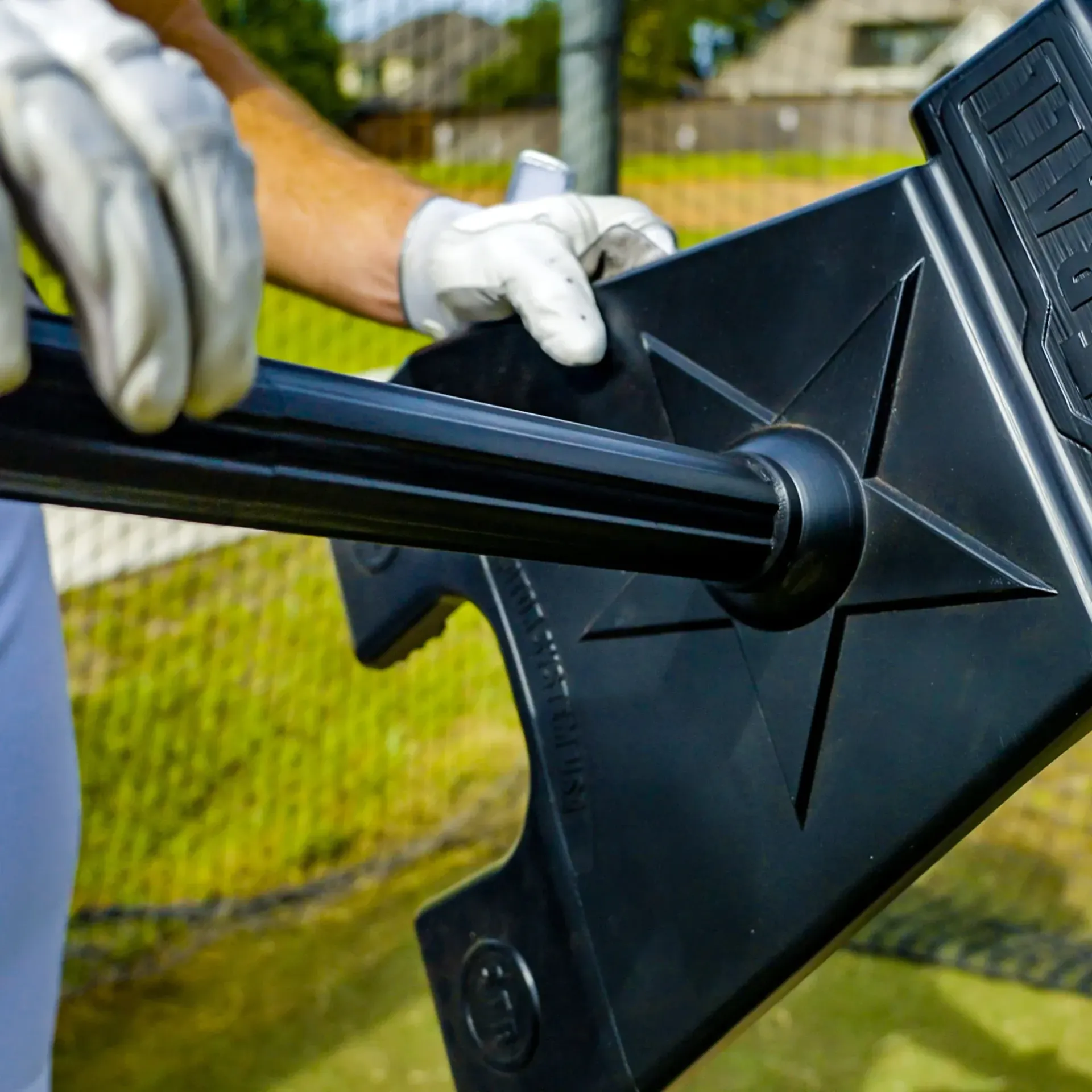 A person wearing white gloves is holding a black pole